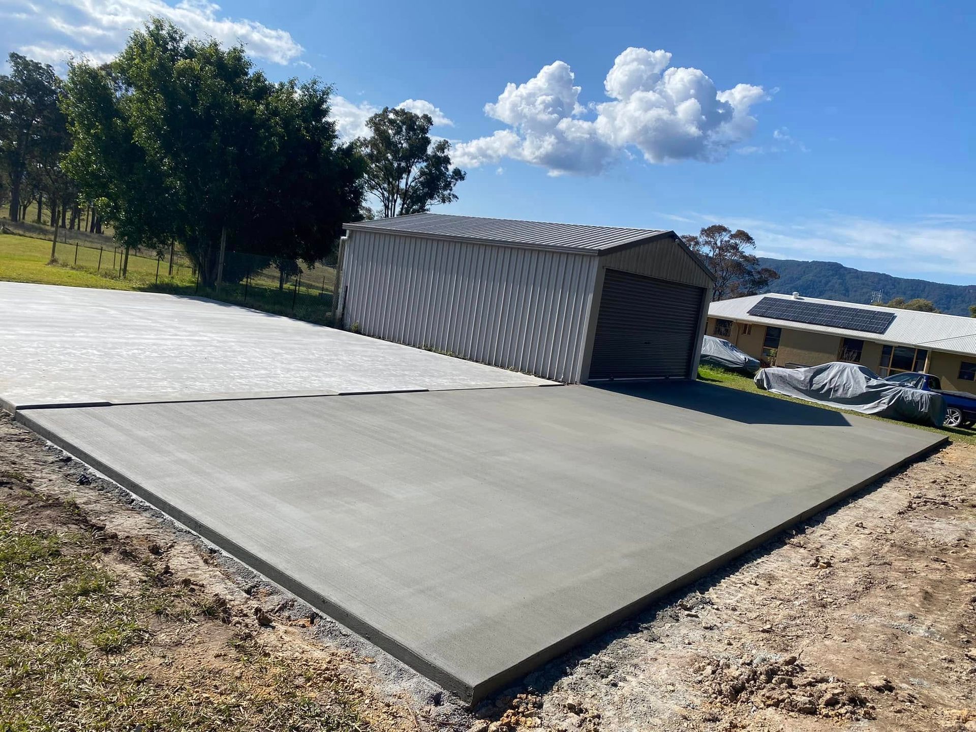 Newly poured concrete slab in front of a metal shed under a blue sky — Rhyno’s Concreting In Old Bar, NSW