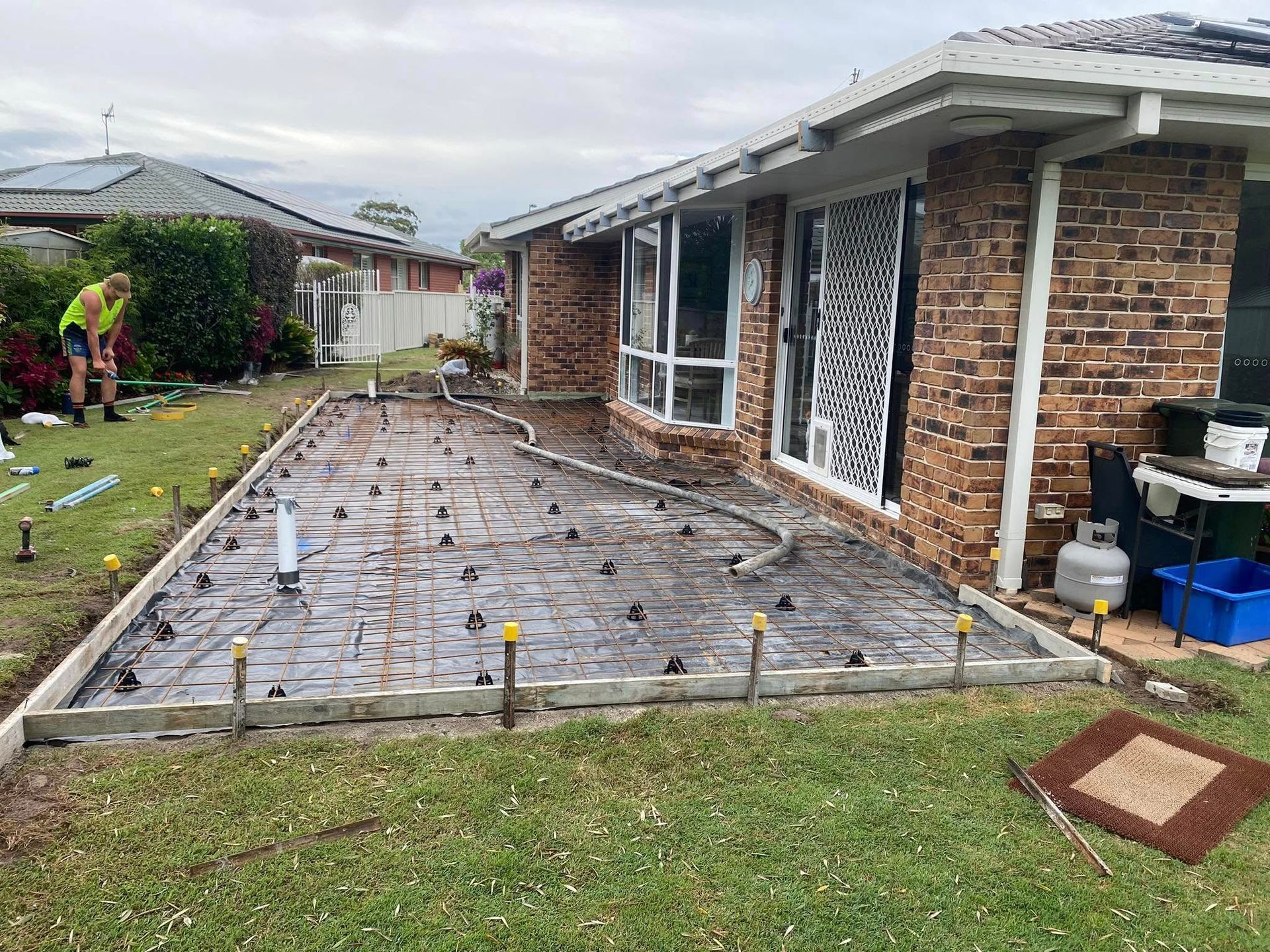 Concrete Slab Being Poured for a Patio Next to a Brick House — Rhyno’s Concreting In Old Bar, NSW