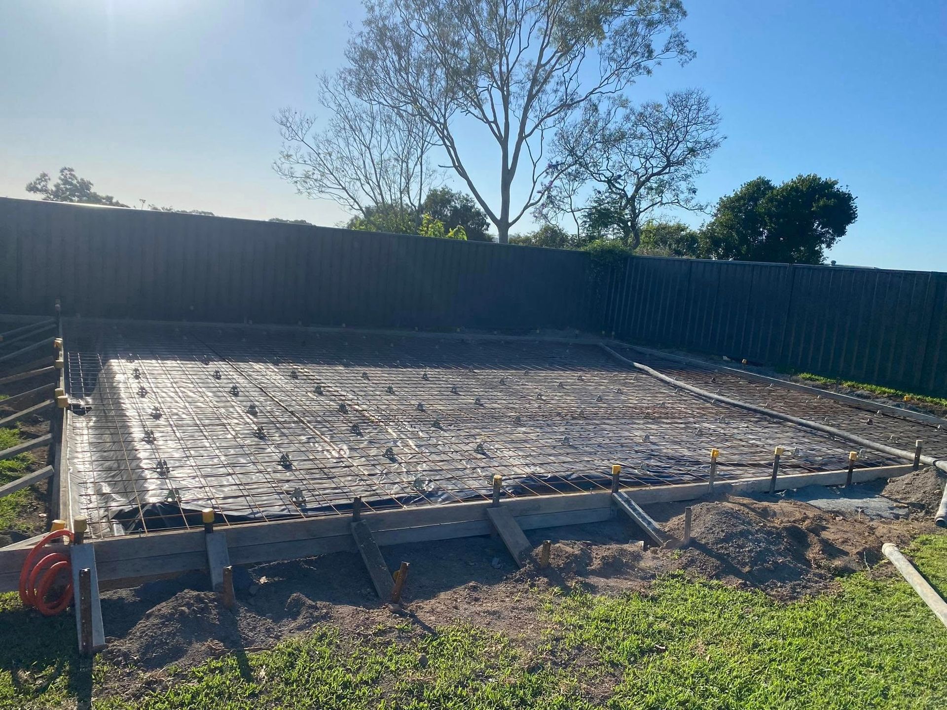 Concrete Foundation with Rebar Framework, Wooden Formwork, and Surrounding Grass, Near a Fence — Rhyno’s Concreting In Old Bar, NSW
