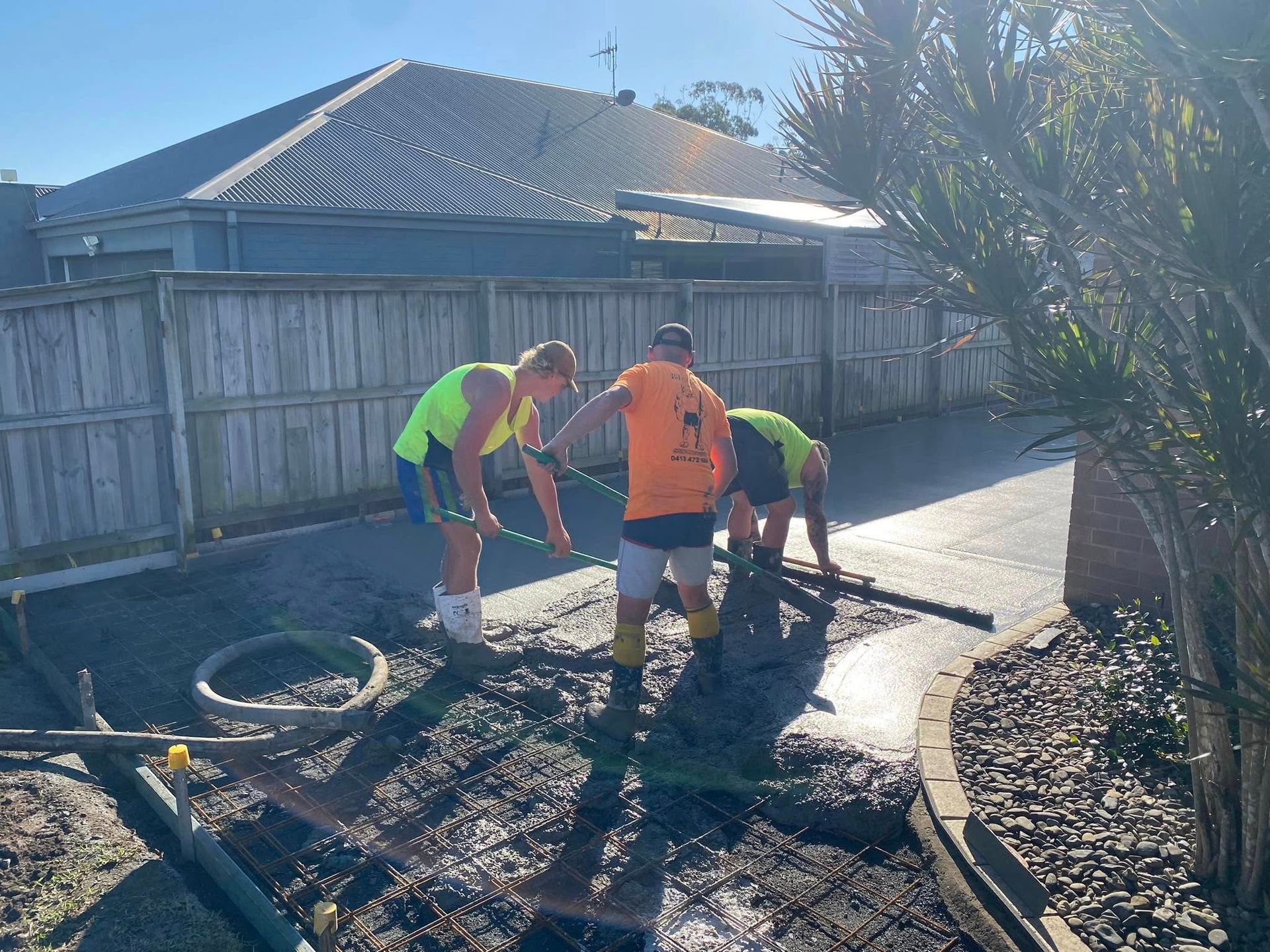 Three Construction Workers Pouring Concrete on A Driveway. Sunny Day — Rhyno’s Concreting In Old Bar, NSW