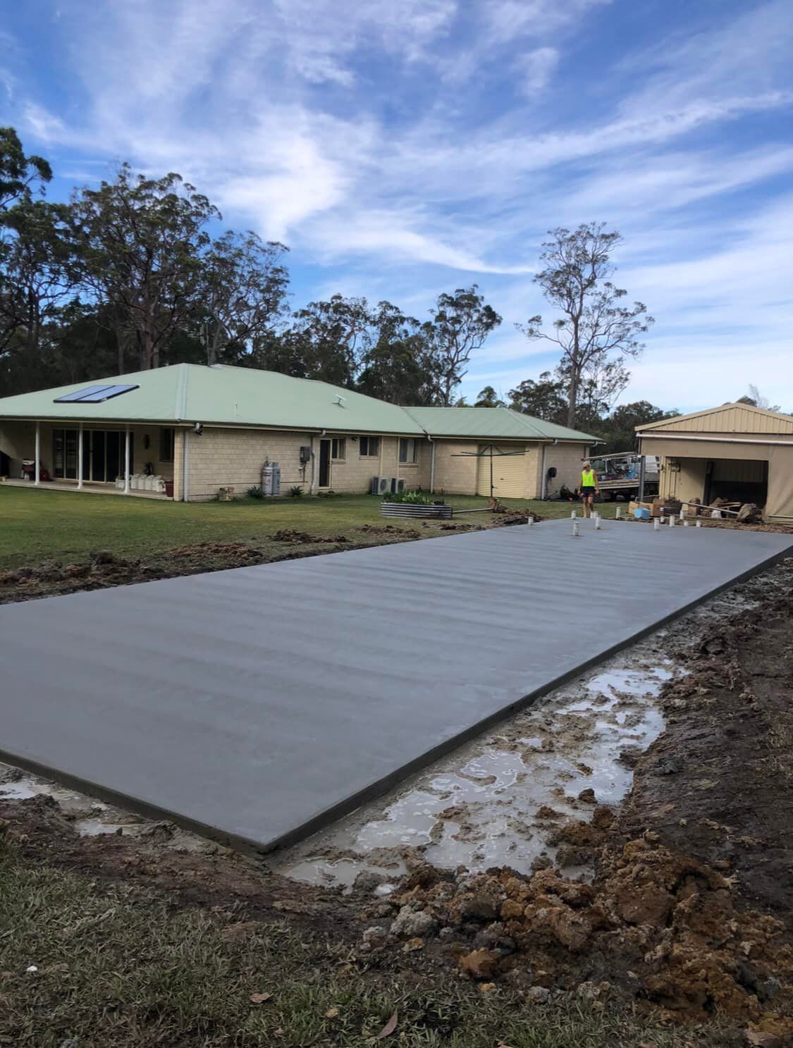 Freshly Poured Concrete Slab in A Backyard, Near a House and Garage, with Overcast Sky — Rhyno’s Concreting In Old Bar, NSW