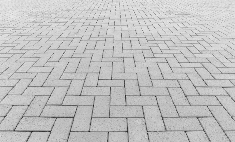 Grey brick pavers arranged in a herringbone pattern, receding into the distance — Rhyno’s Concreting In Old Bar, NSW