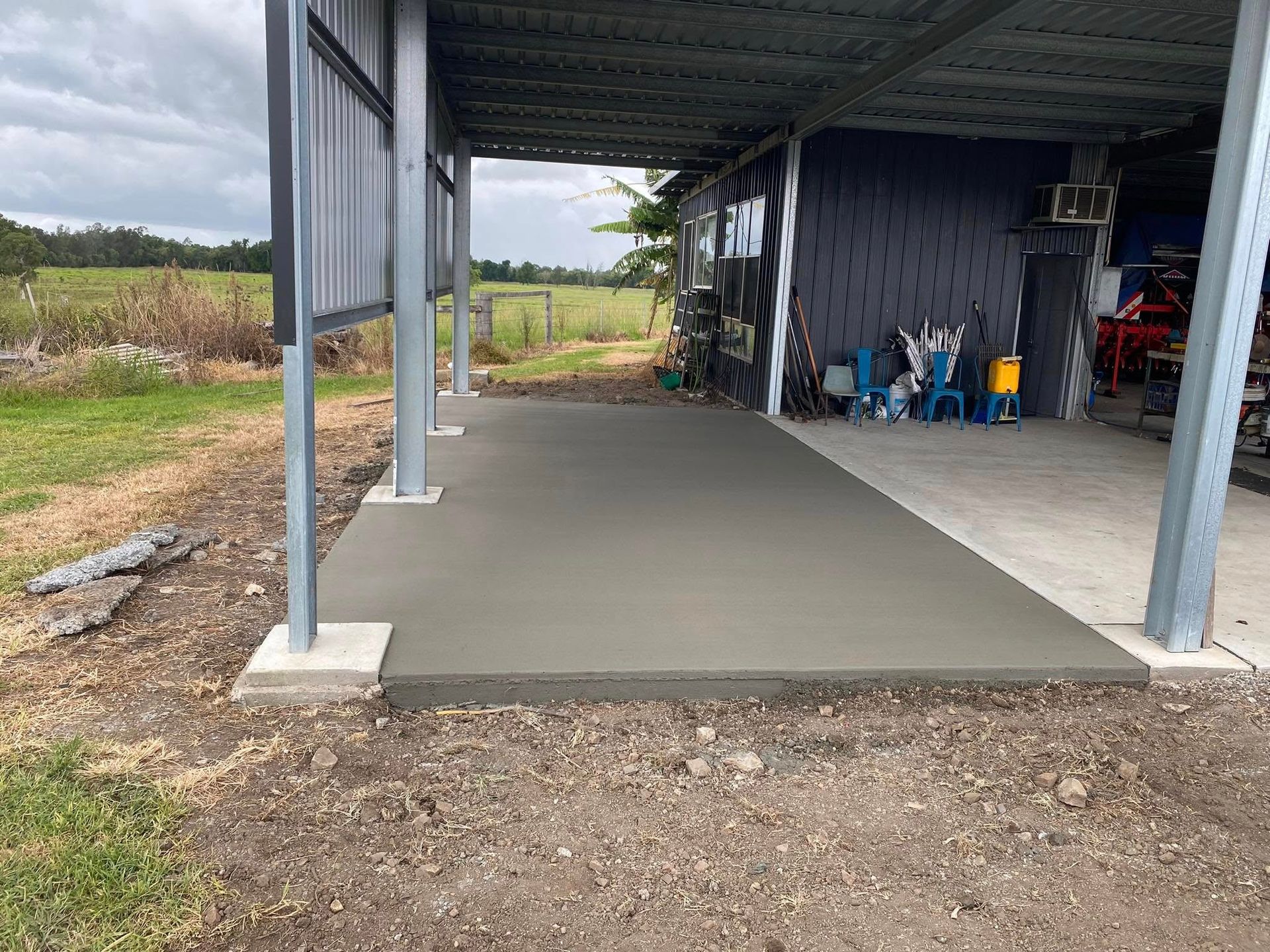 A Newly Poured Concrete Slab Under a Metal Carport, Outdoors — Rhyno’s Concreting In Old Bar, NSW
