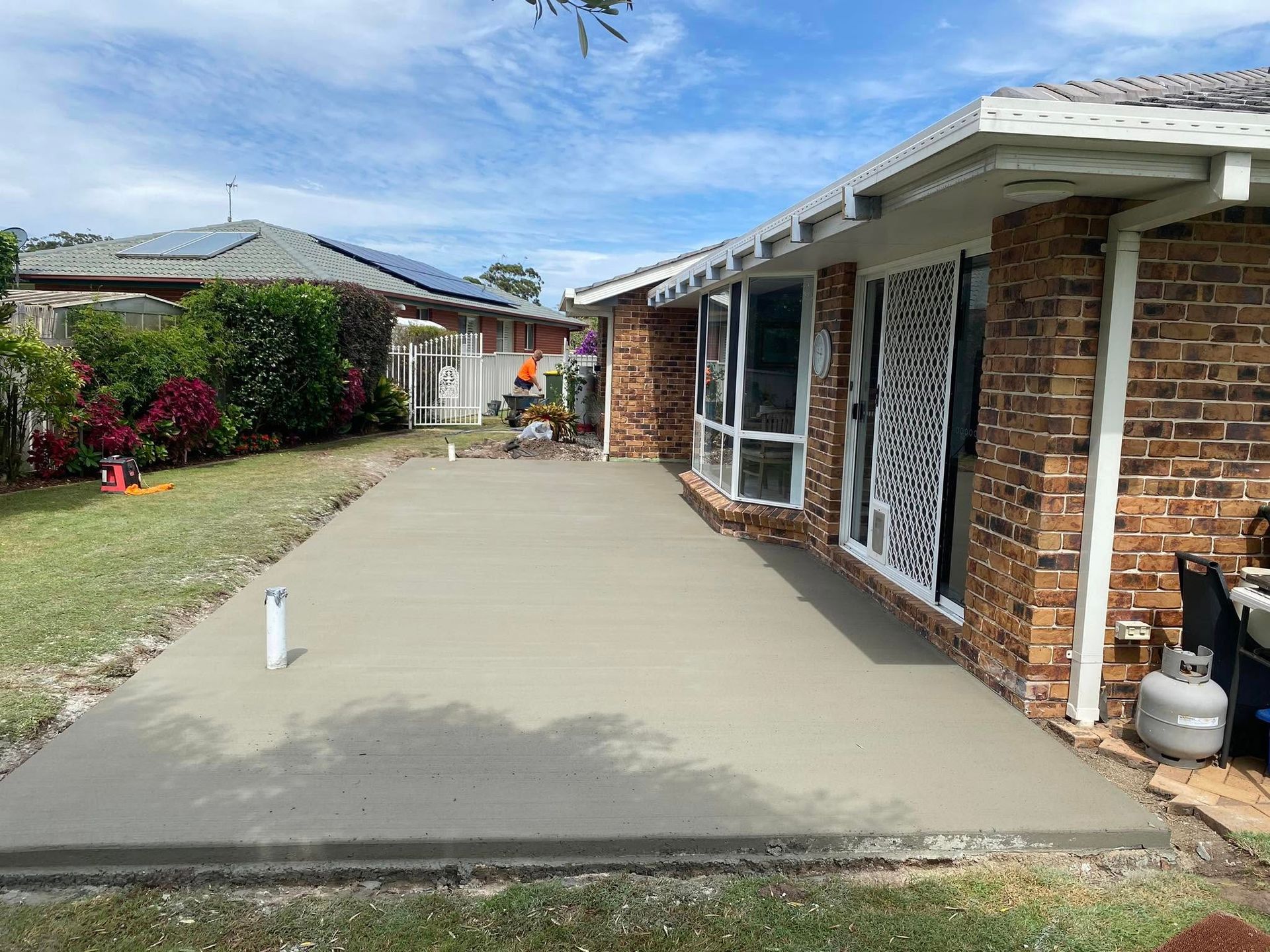 Newly poured concrete slab with metal shed, set against a hillside with blue sky and clouds — Rhyno’s Concreting In Old Bar, NSW