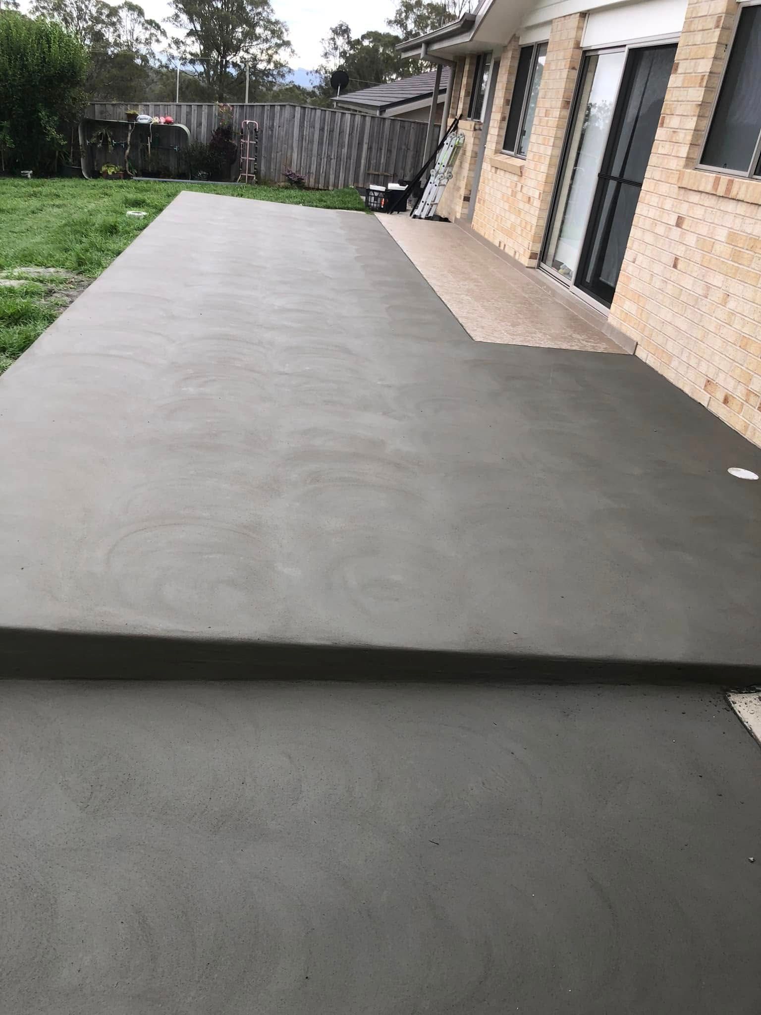 Newly Poured Concrete Patio Next to A Brick House. a Step Leads up To a Higher Level — Rhyno’s Concreting In Old Bar, NSW