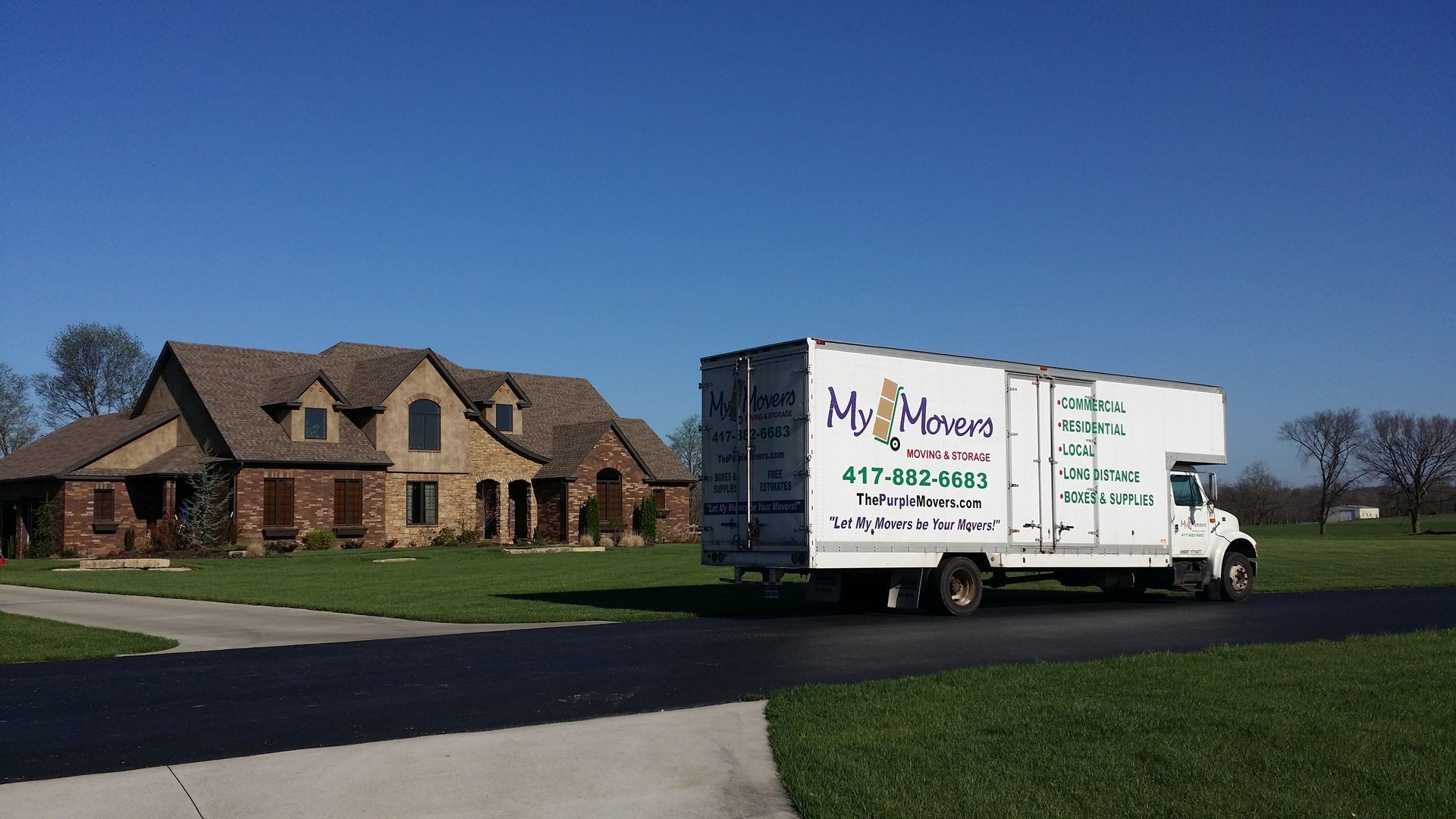 Moving truck in front of a large house on a sunny day