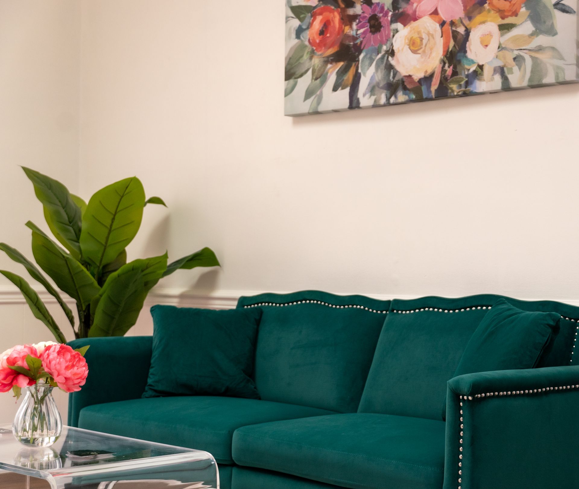 A living room with a green couch and a painting on the wall