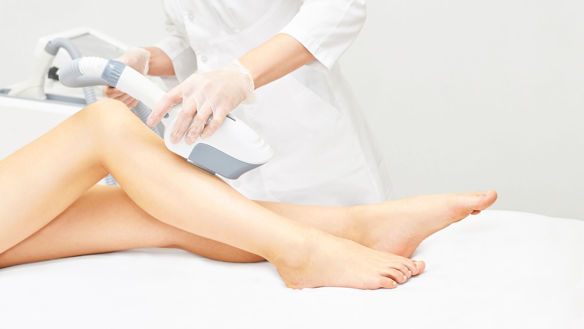 A woman is getting a laser hair removal treatment on her legs.