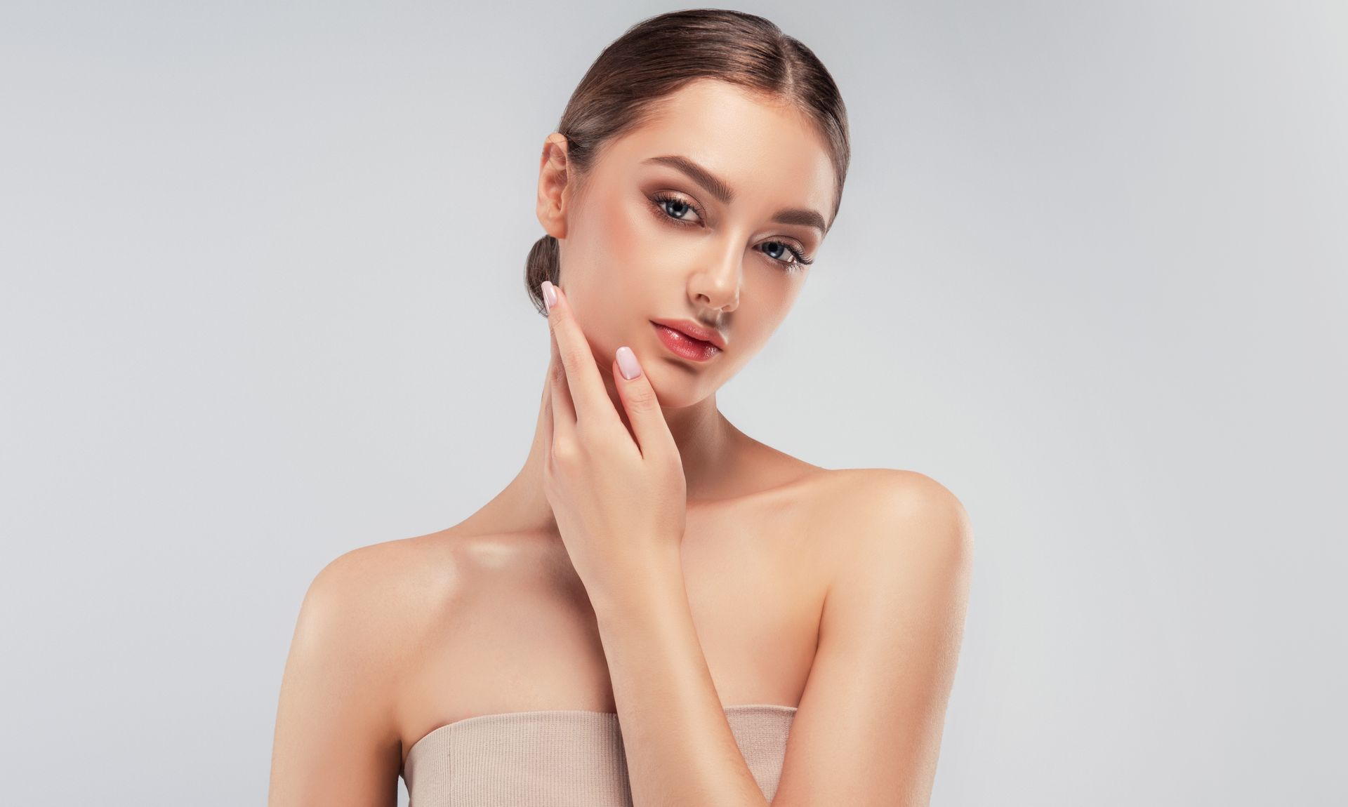 A woman is touching her face with her hand and looking at the camera.