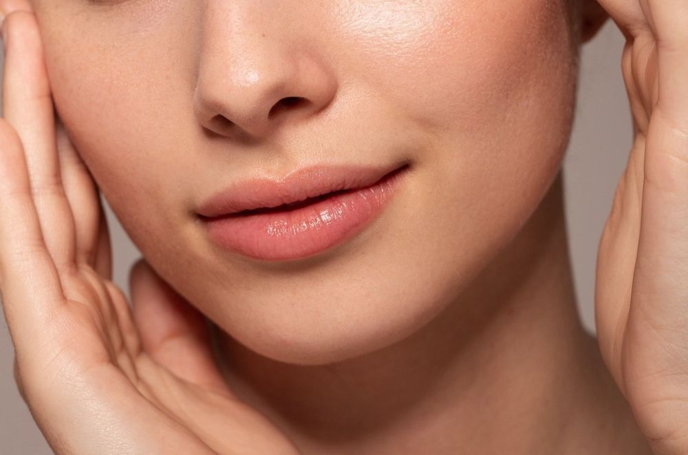 A close up of a woman 's face with her hands on it.