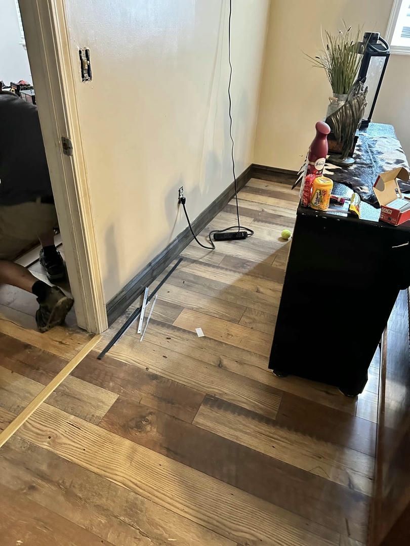 A person is working on a wooden floor in a room.