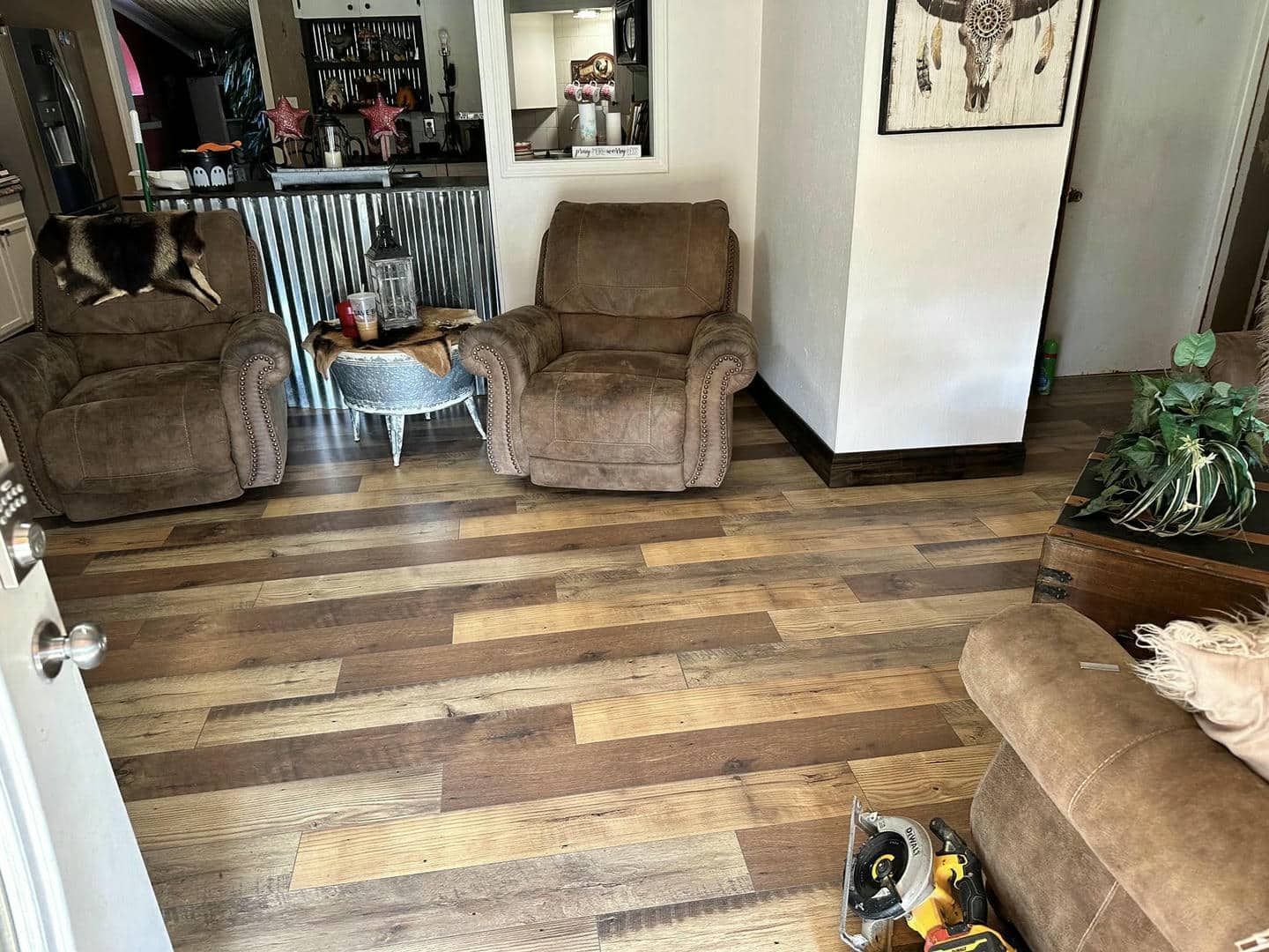 A living room with a wooden floor , two chairs , a couch and a table.