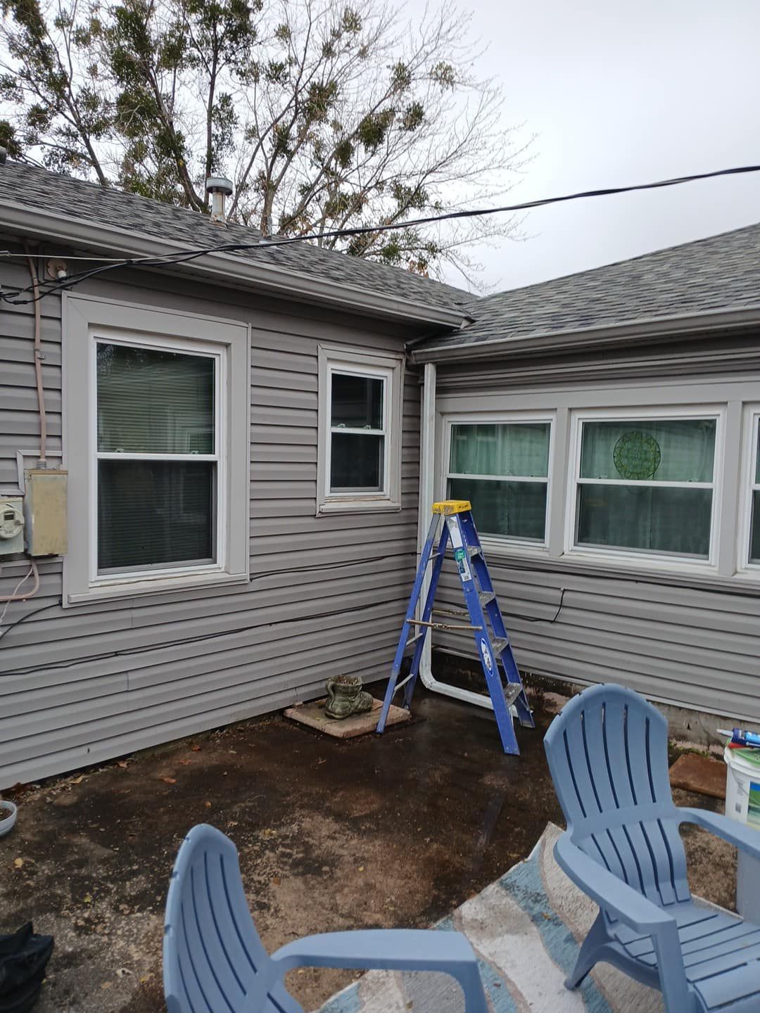 A house with a ladder and chairs in front of it.