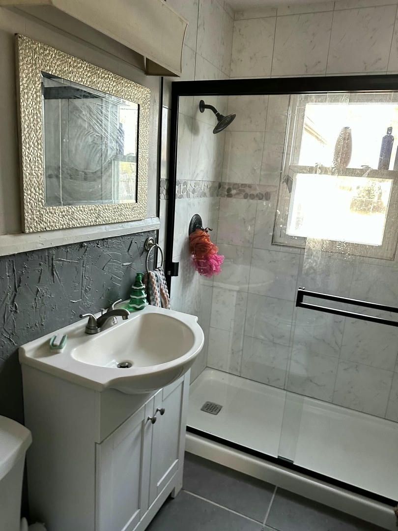 A bathroom with a sink , toilet , shower and mirror.