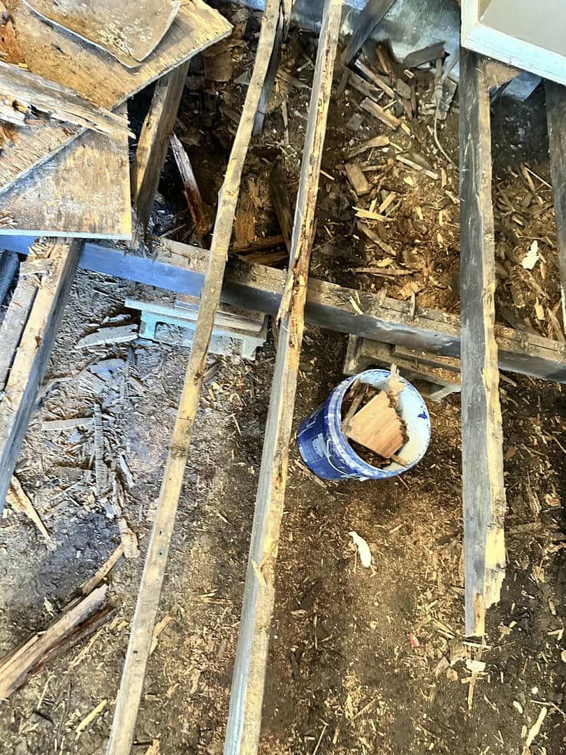 A blue bucket is sitting on the ground next to a pile of wood.