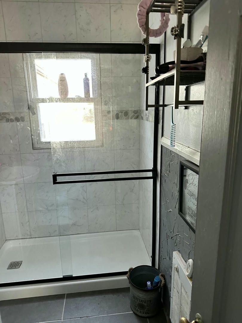A bathroom with a walk in shower and a window.