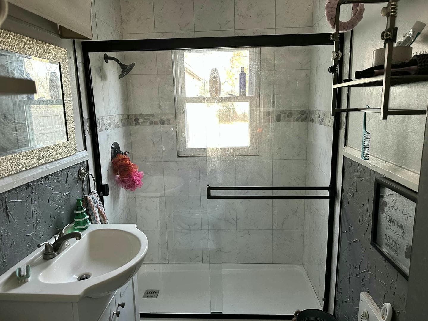 A bathroom with a sink , toilet , shower and window.