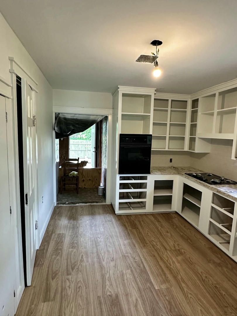A kitchen with wooden floors and white cabinets is being remodeled.