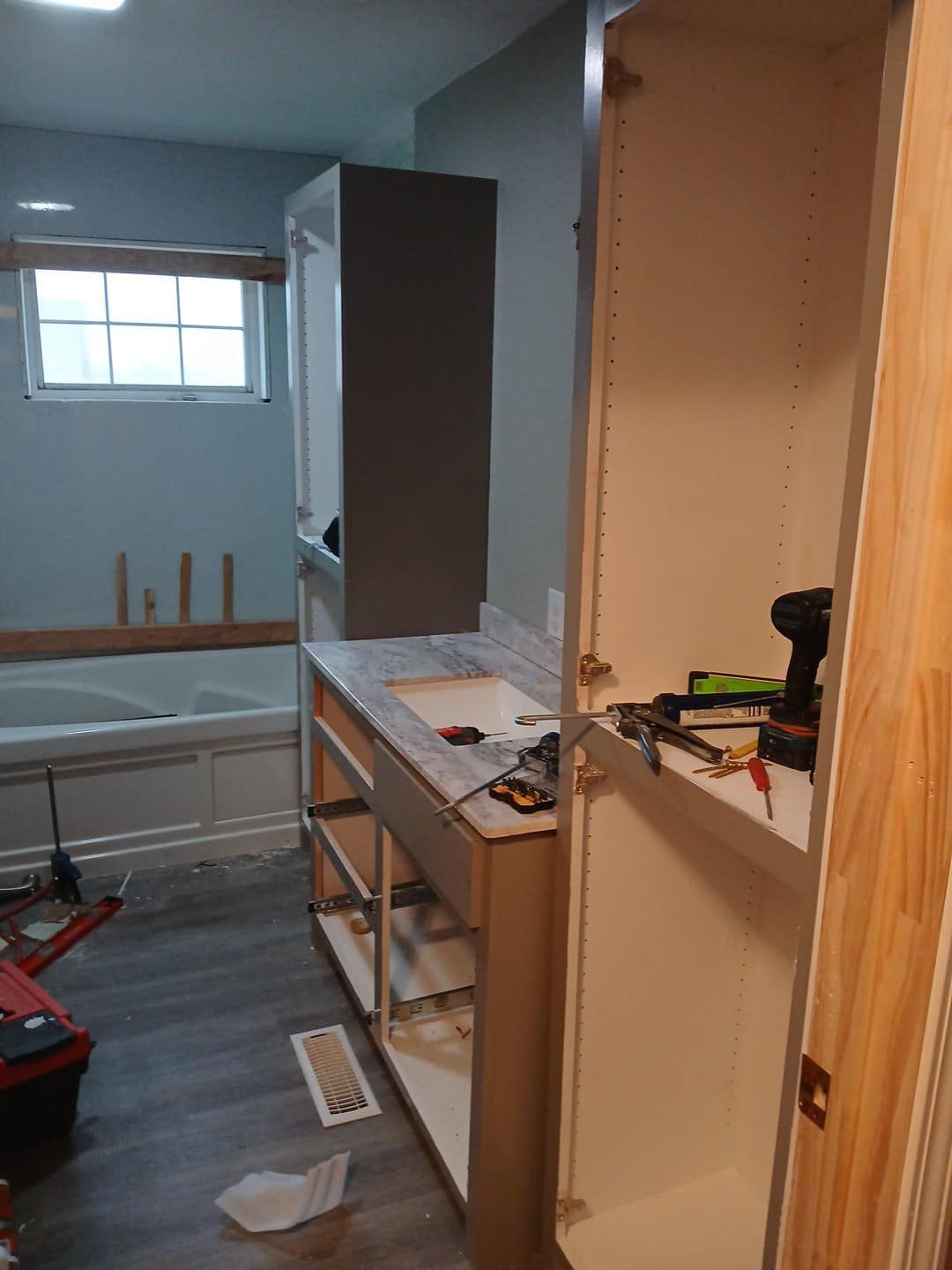 A bathroom under construction with a sink , cabinets , and a window.