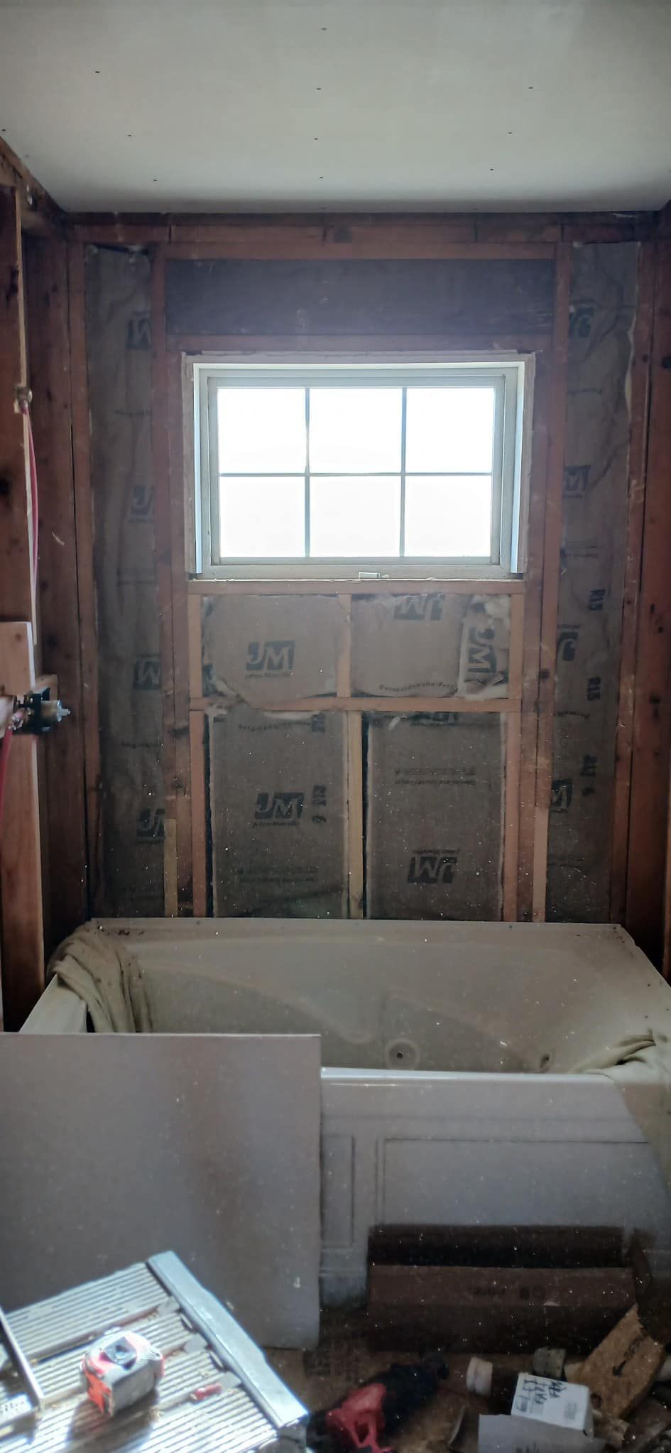 A bathtub is being built in a bathroom with a window.