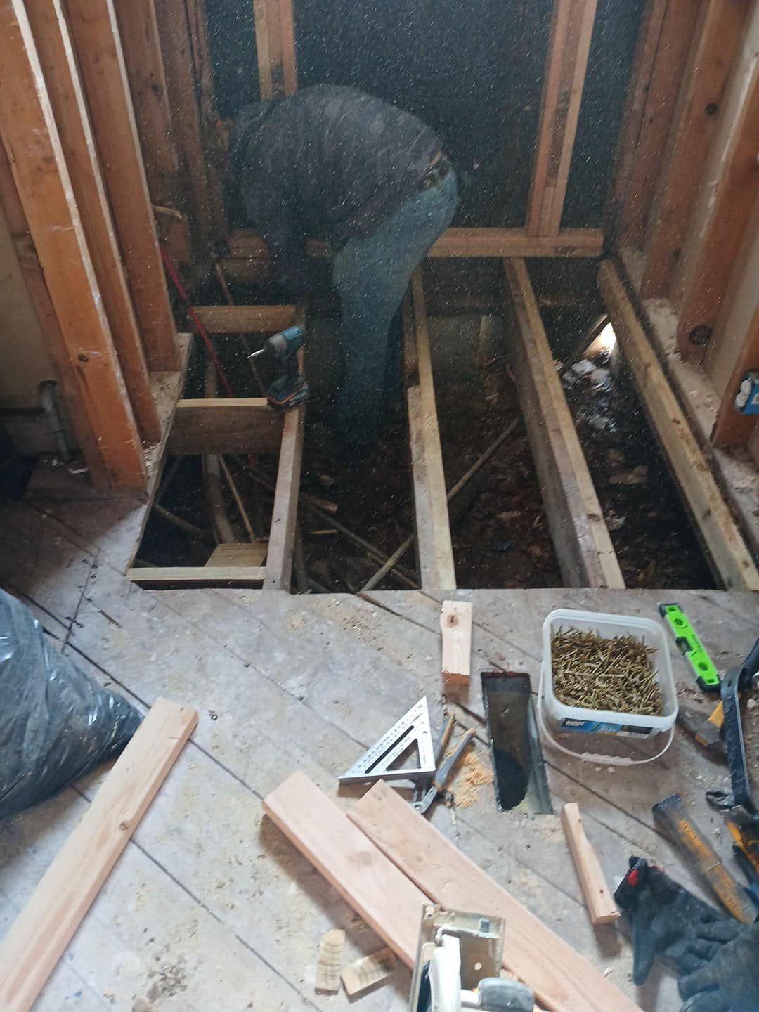 A man is working on a wooden floor in a room.