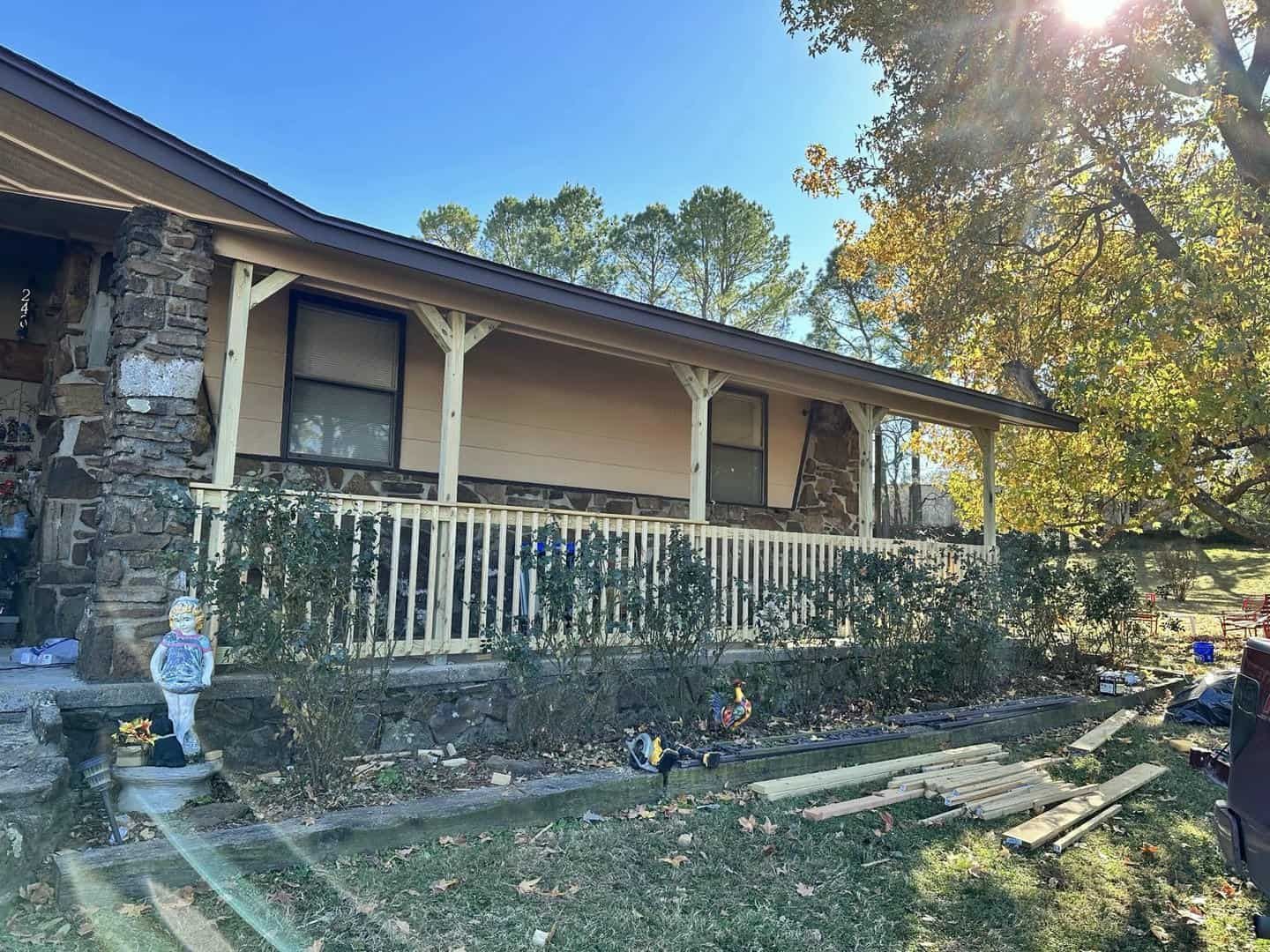 A house with a porch and a fence in front of it.