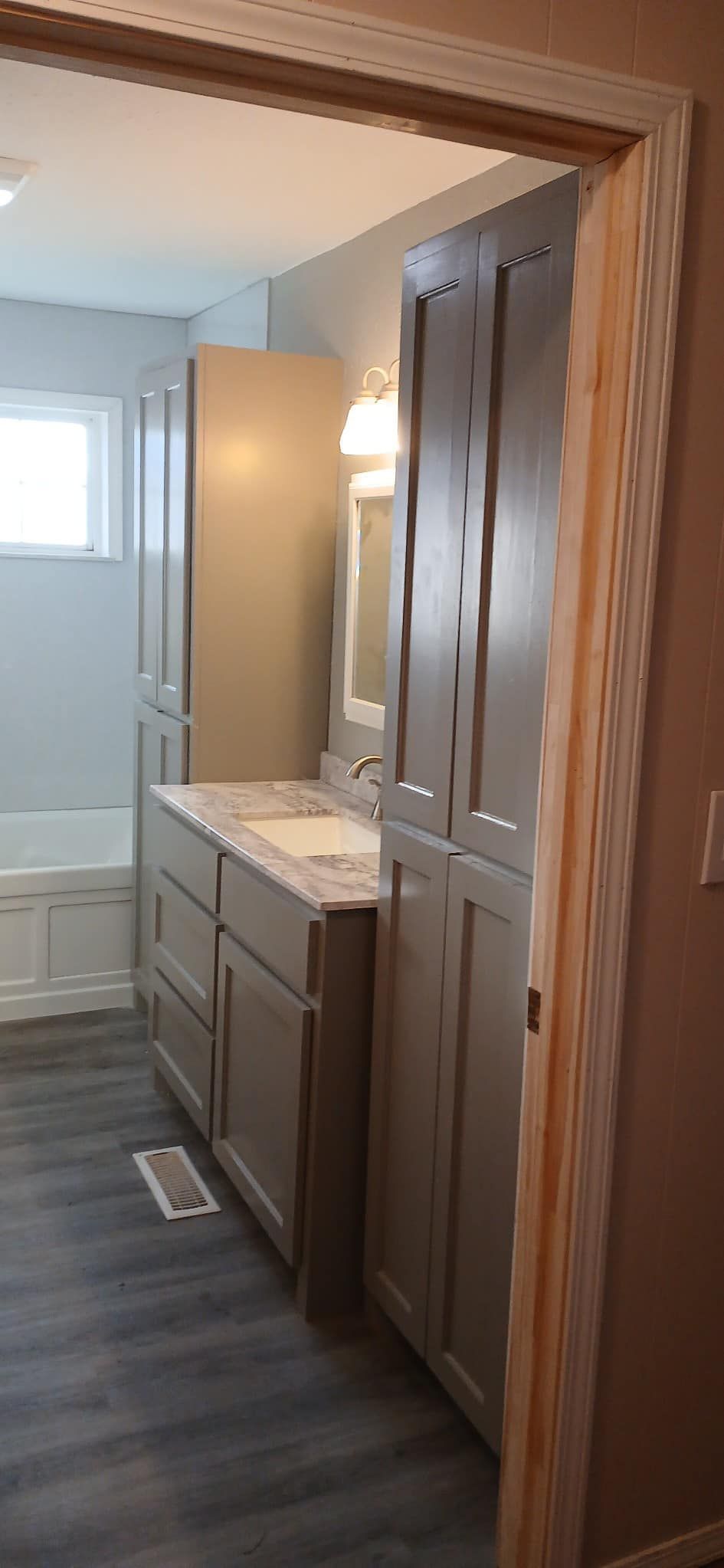 A bathroom with a sink , cabinets , and a tub.