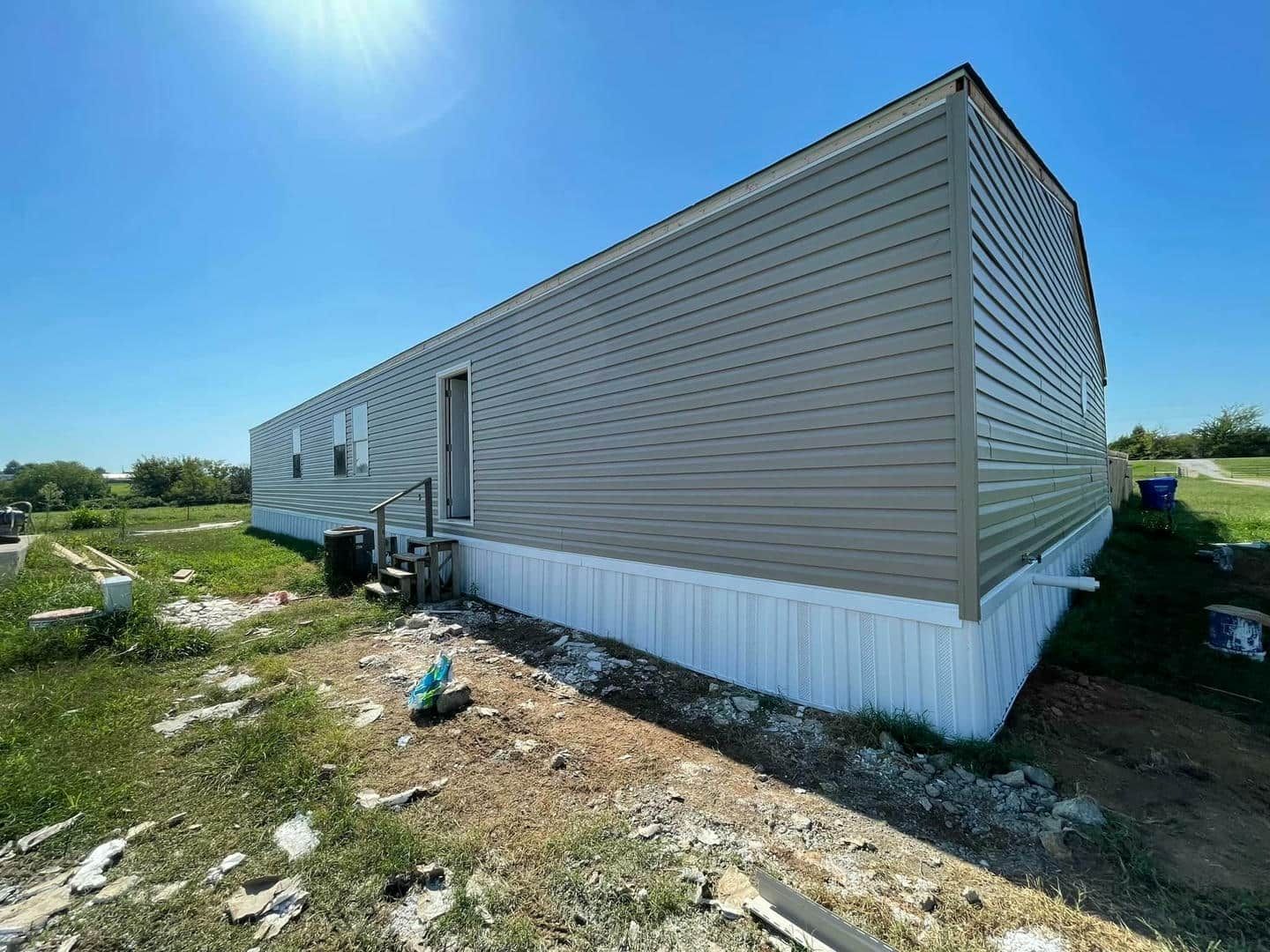 A mobile home is sitting on top of a dirt field.