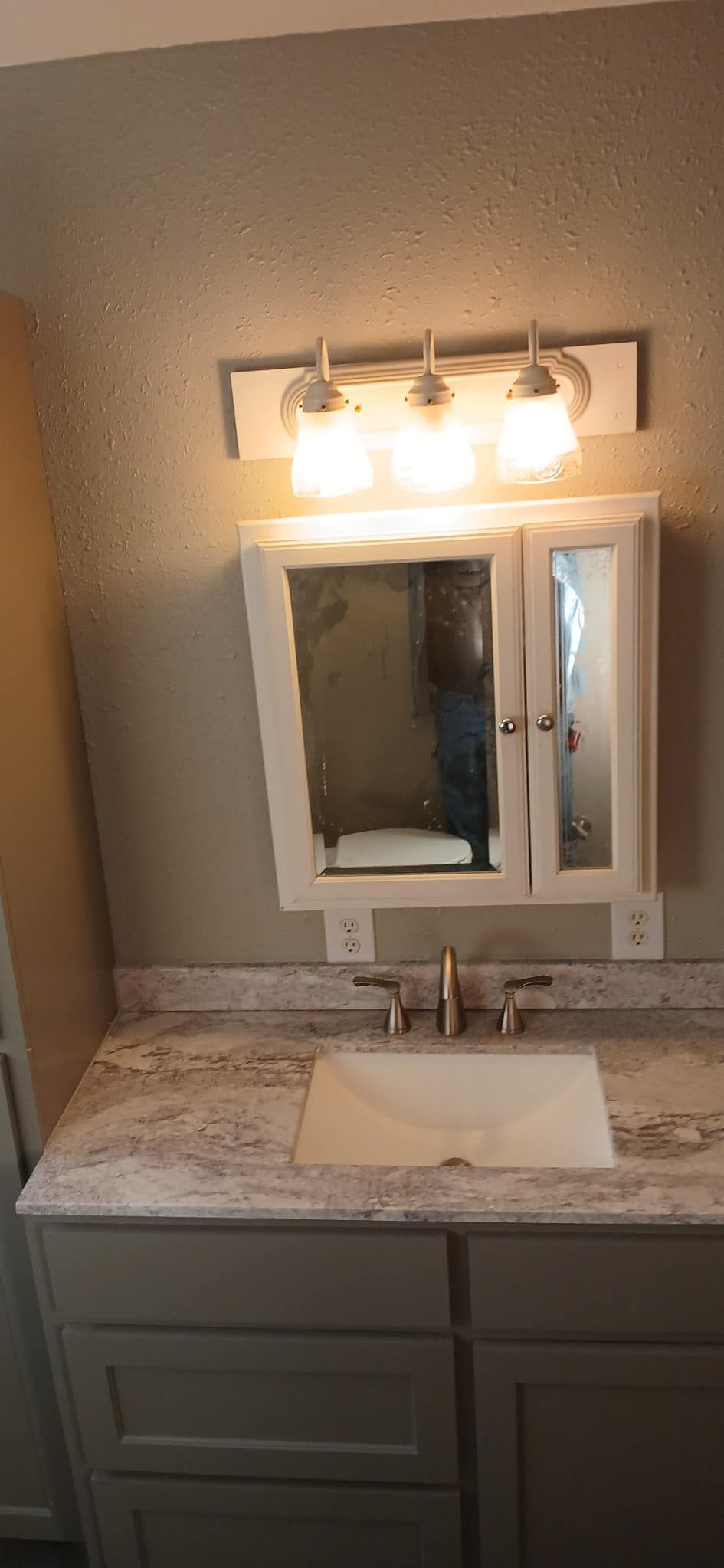 A bathroom with a sink , mirror and cabinet.