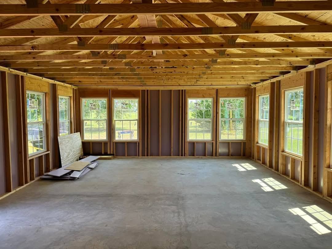An empty room with a lot of windows and wooden beams.