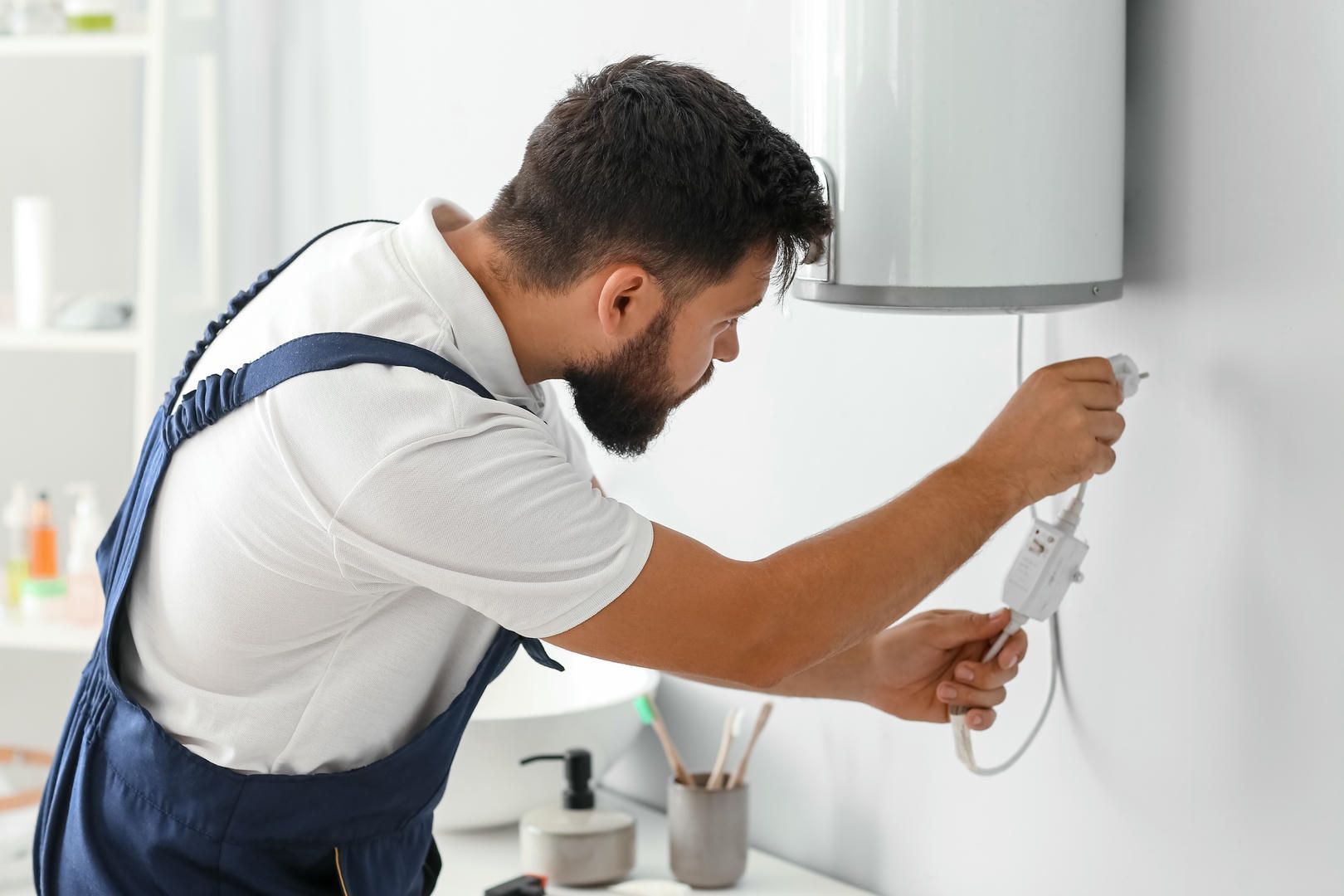A man is fixing a water heater in a bathroom.
