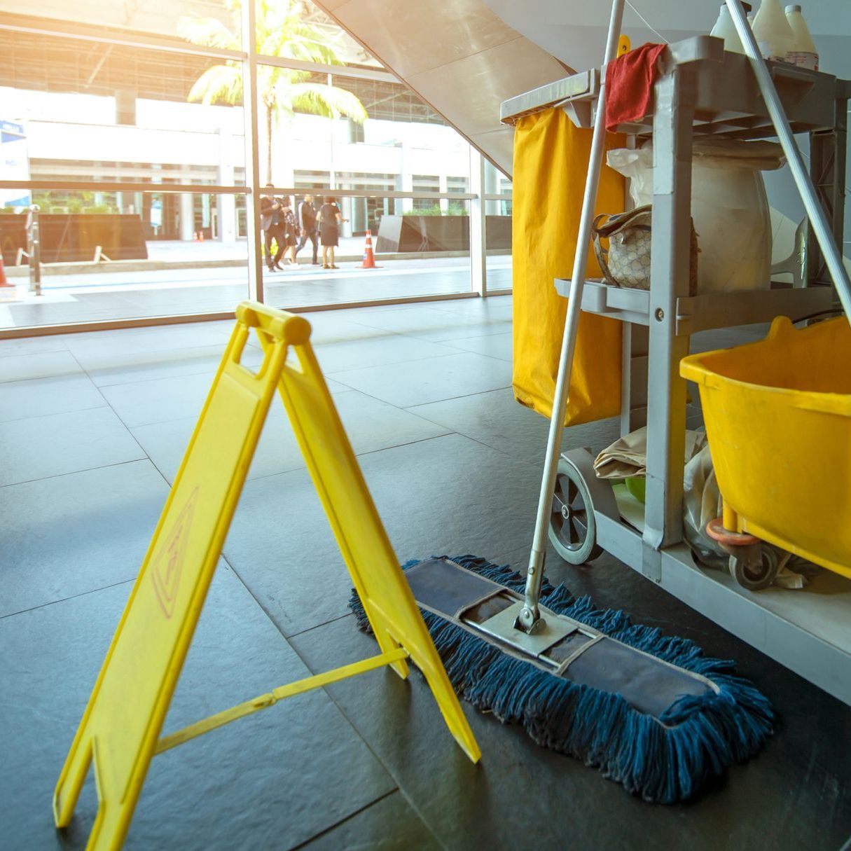 Un cartello giallo di attenzione è accanto a uno straccio e a un secchio