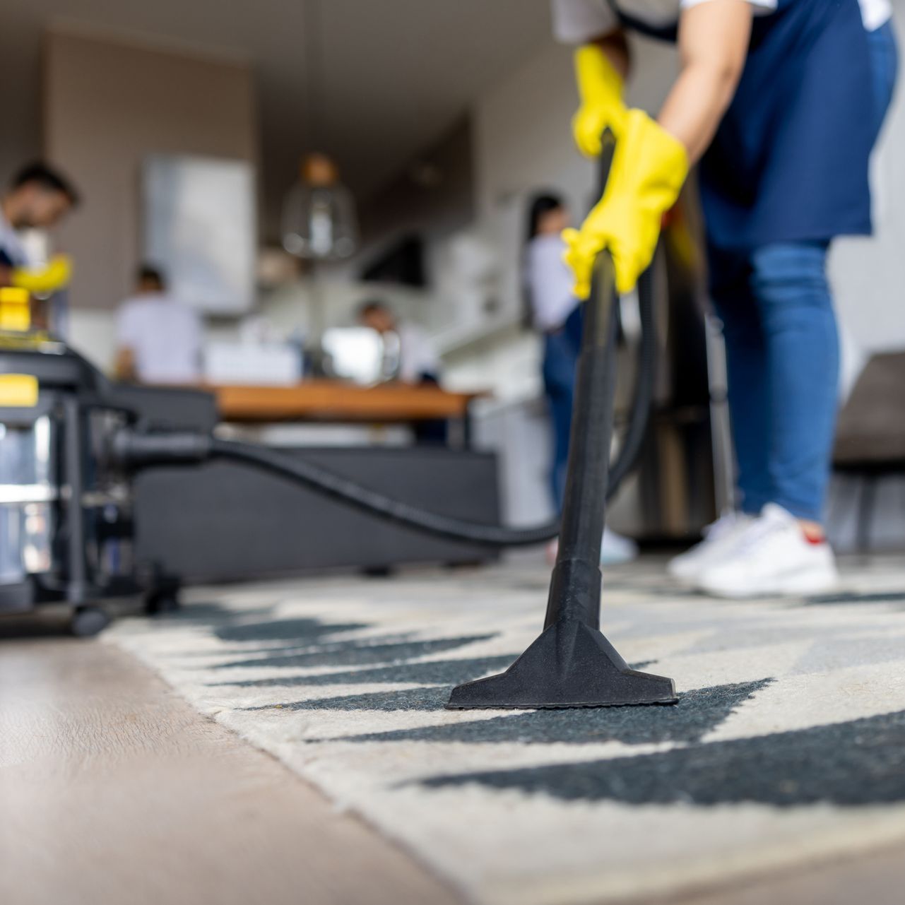 Una donna sta usando un aspirapolvere per pulire un tappeto in un soggiorno.