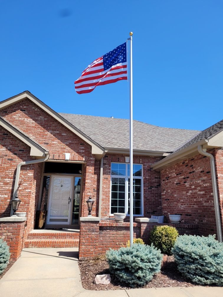 An american flag is flying in front of a brick house