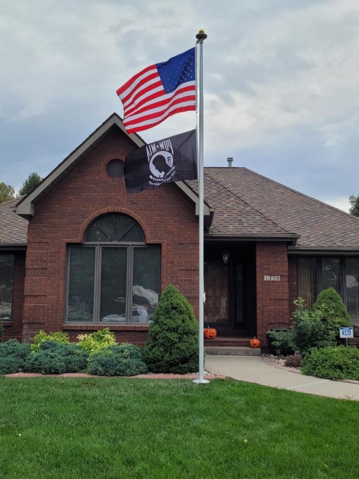 Two flags are flying in front of a brick house