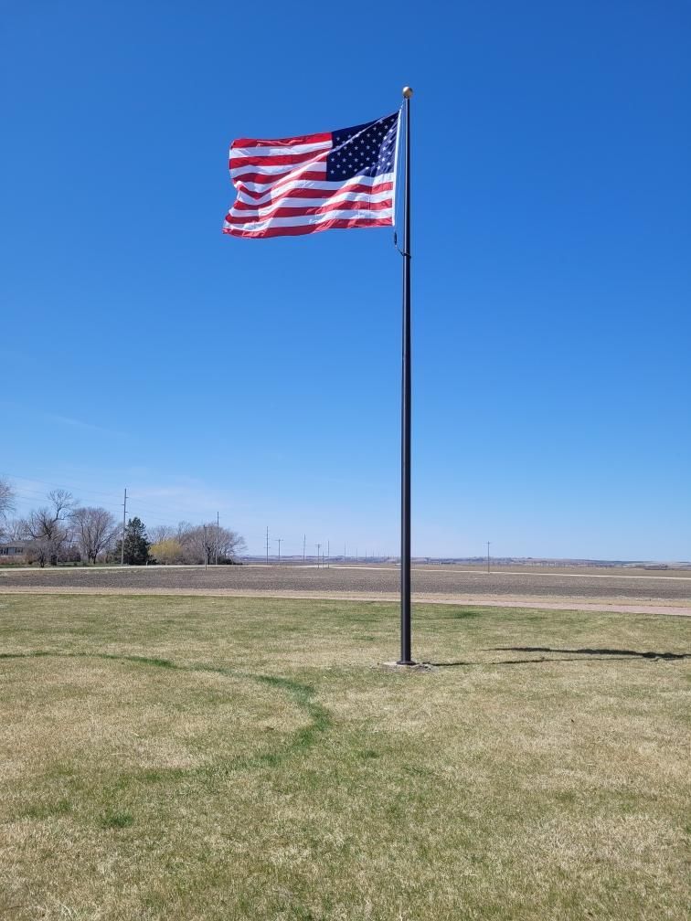 An american flag is flying in the wind in a grassy field
