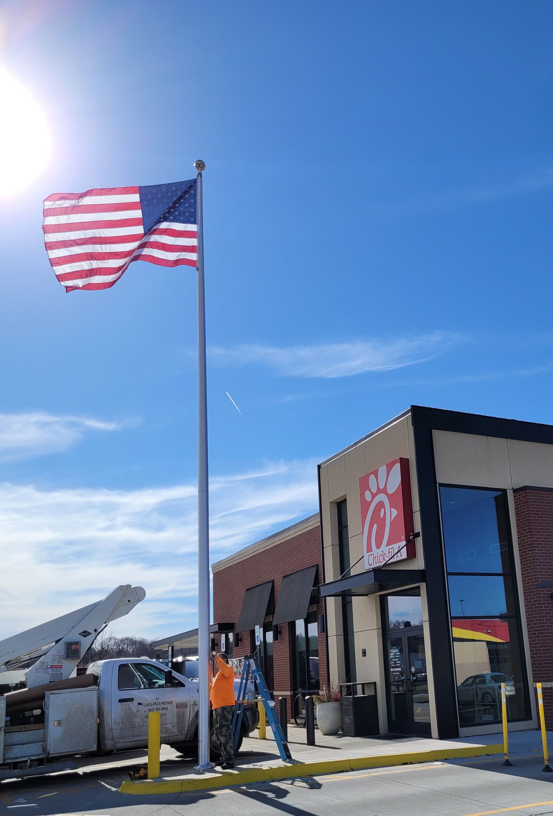 An american flag is flying in front of a chick-fil-a restaurant