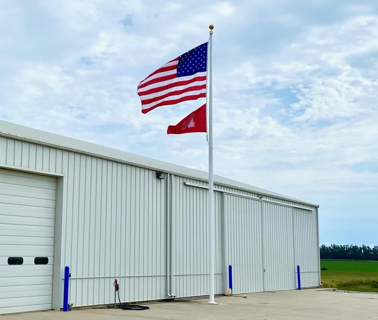 Two american flags are flying in front of a white building