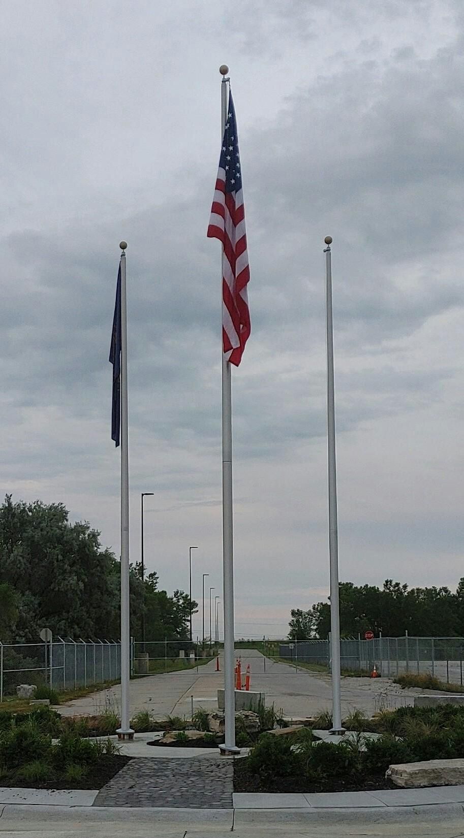 Three american flags are flying in the wind on a cloudy day
