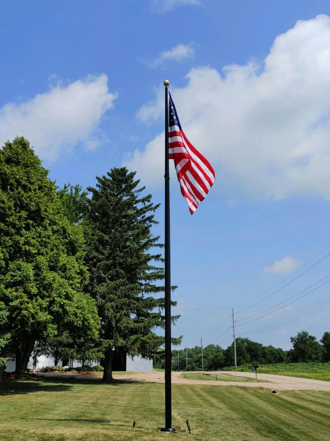 An american flag is flying on a pole in a grassy field