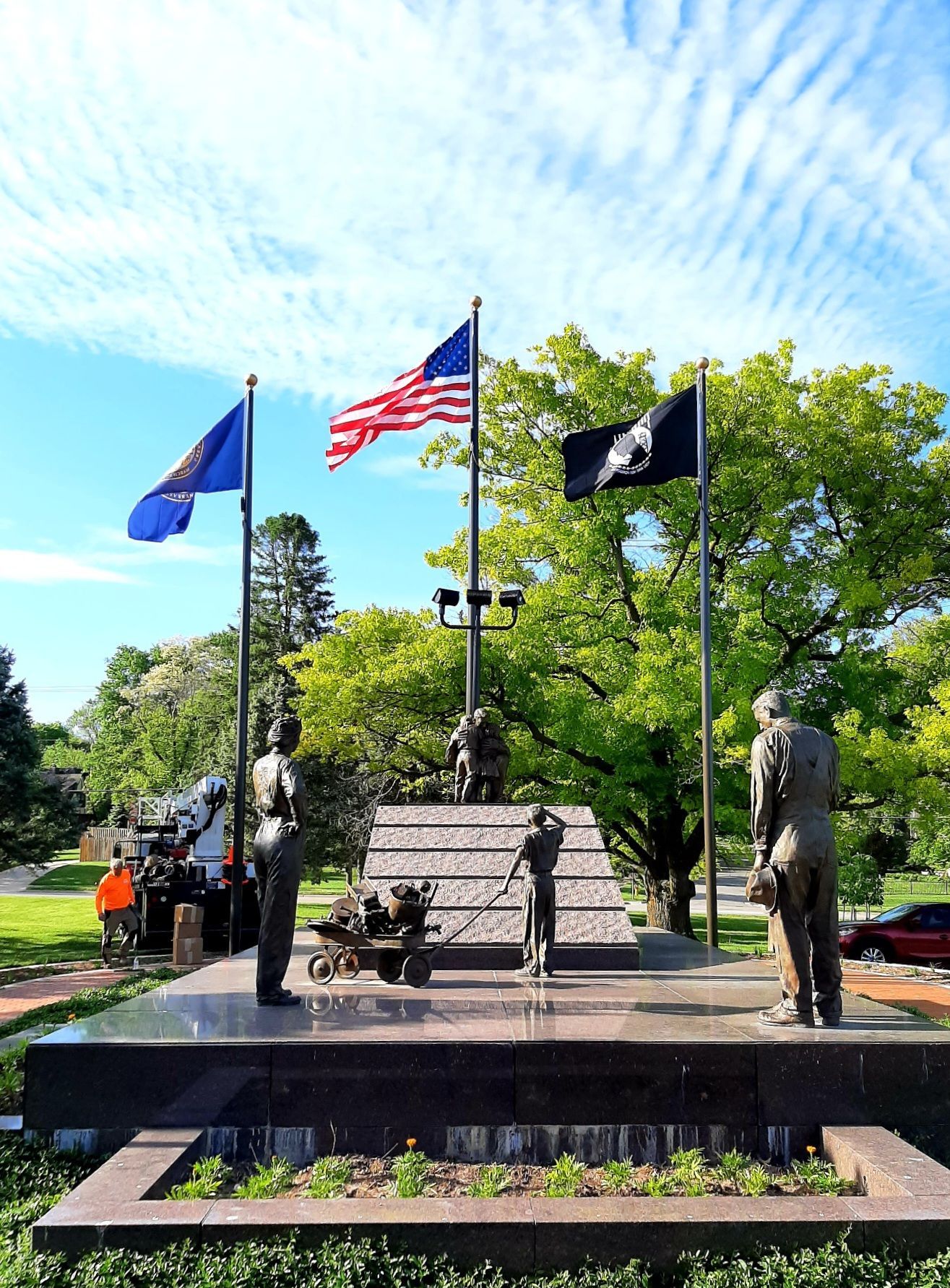 A statue of a man standing in front of a memorial with flags flying in the background.