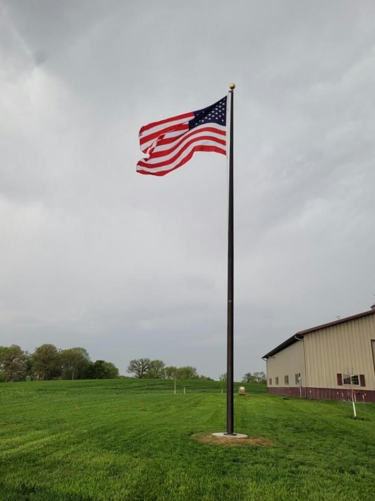 A large american flag is flying in a grassy field