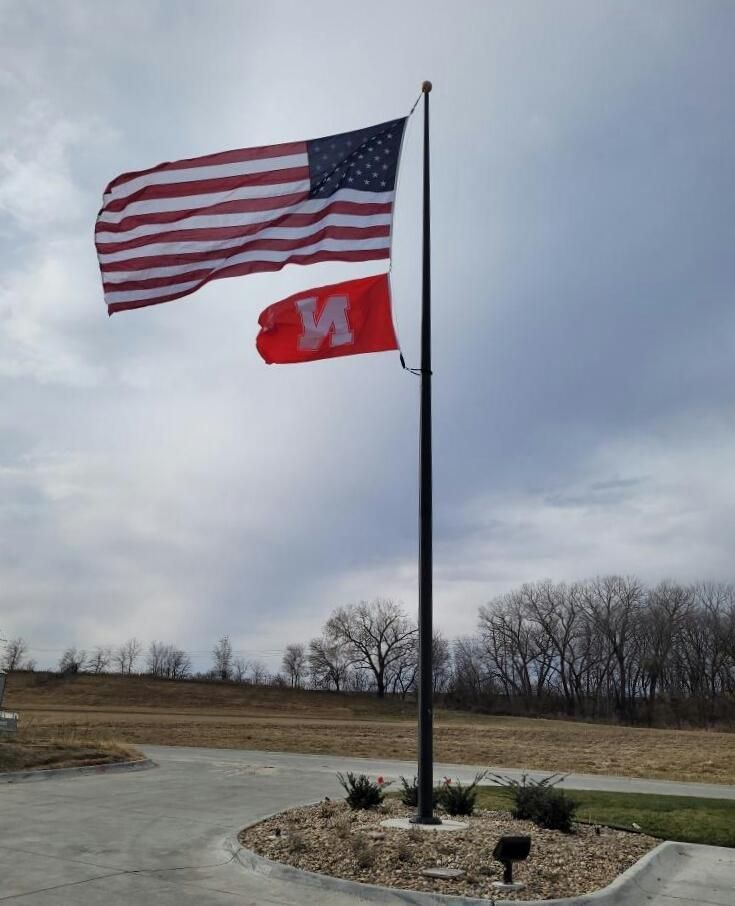 An american flag and a red flag with the letter m on it