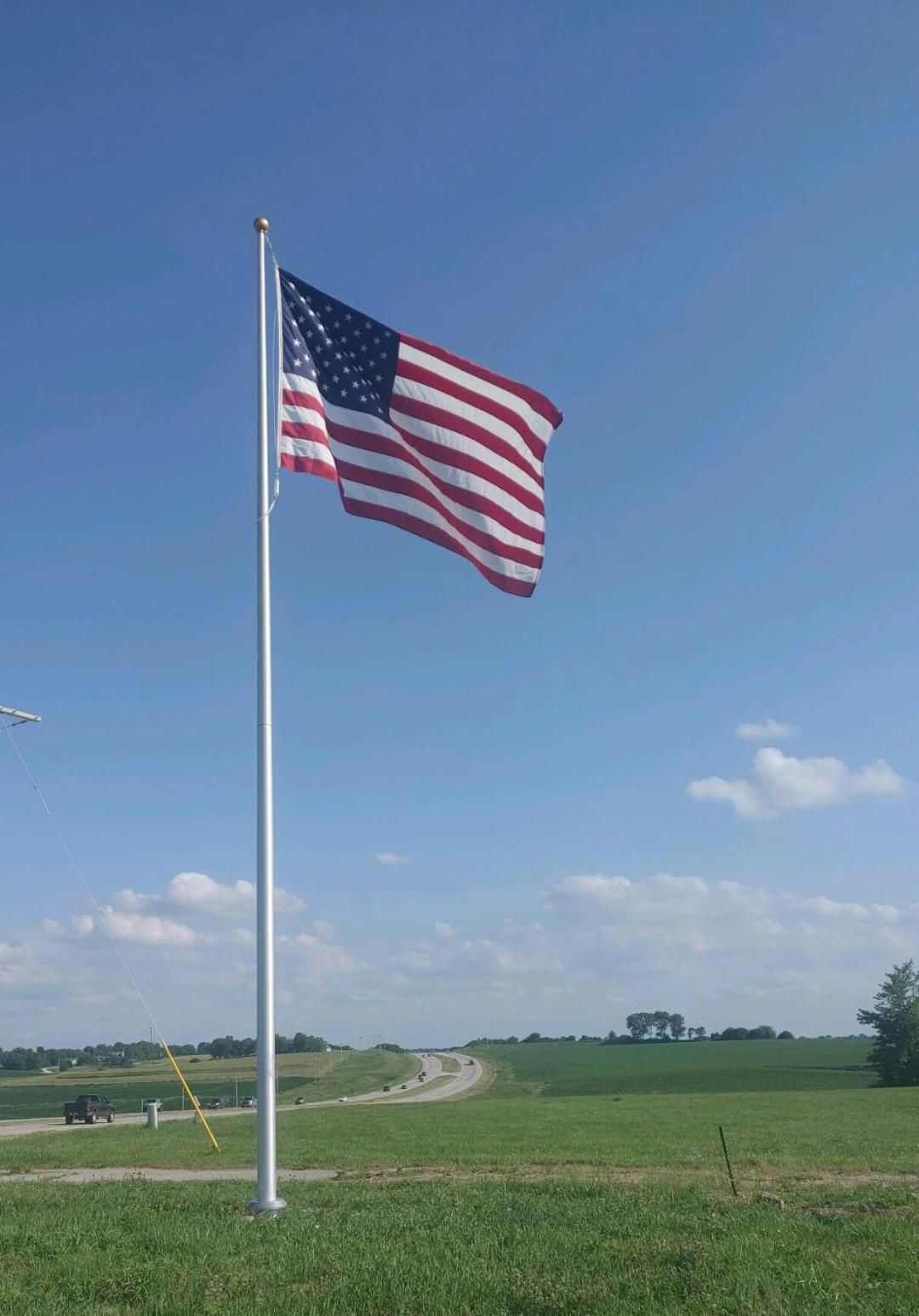 An american flag is flying in the wind in a field.