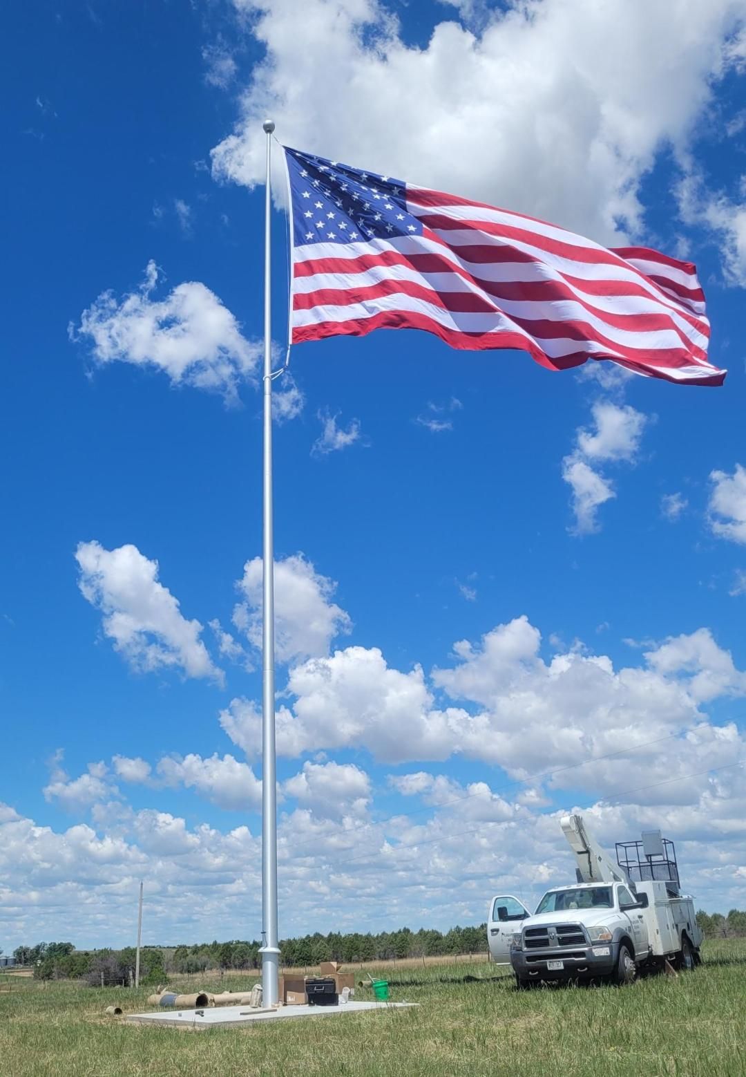 A large american flag is flying in the wind in a field.