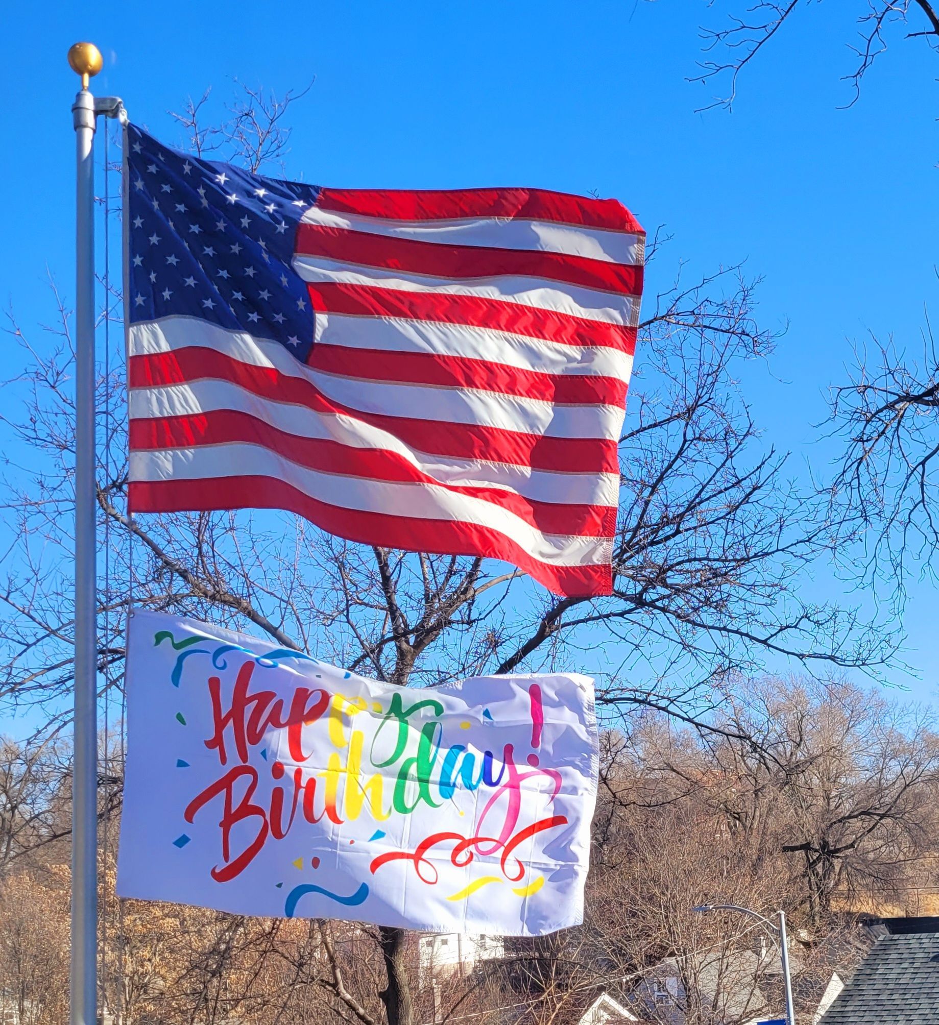 An american flag is flying next to a happy birthday sign