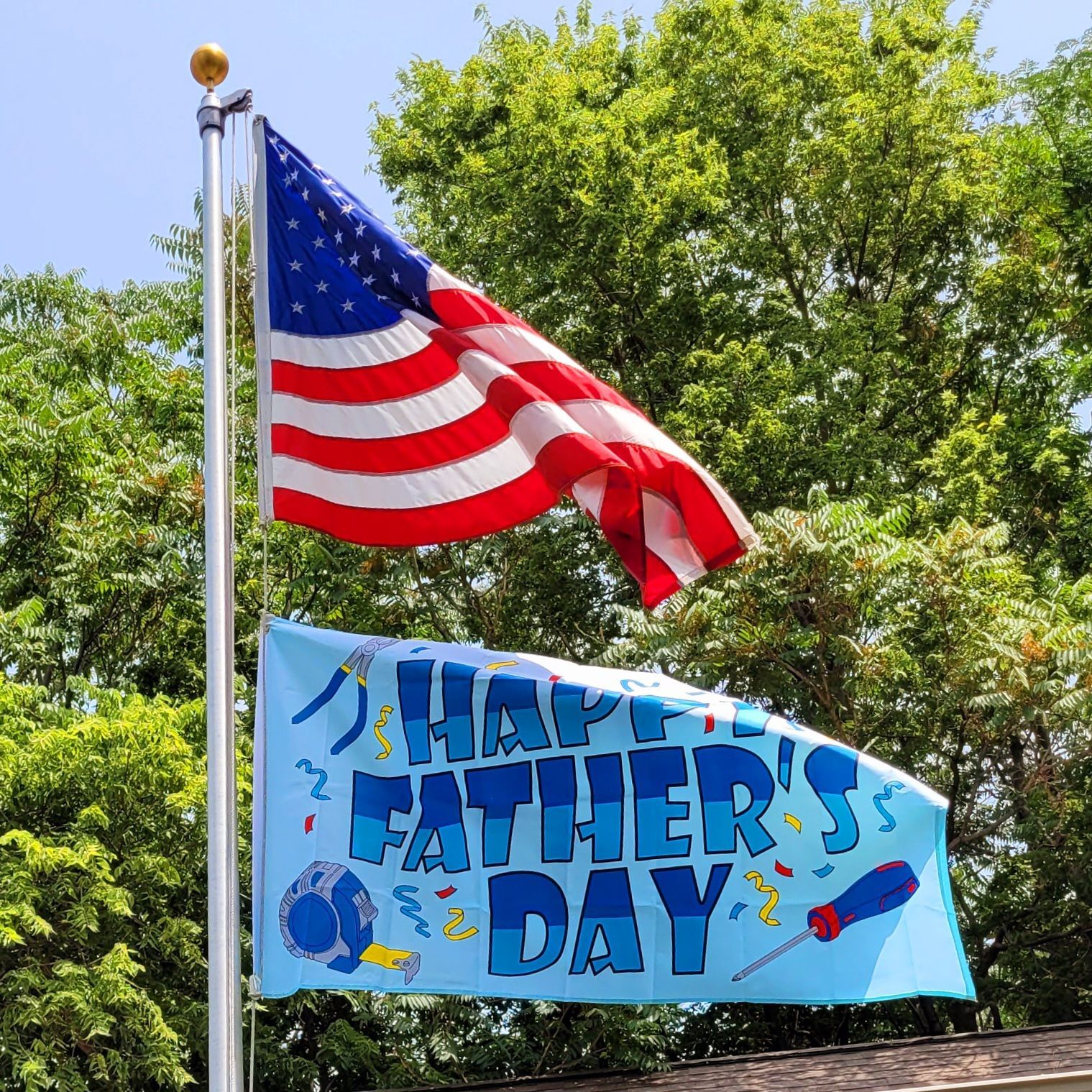 An american flag is flying next to a happy father 's day banner