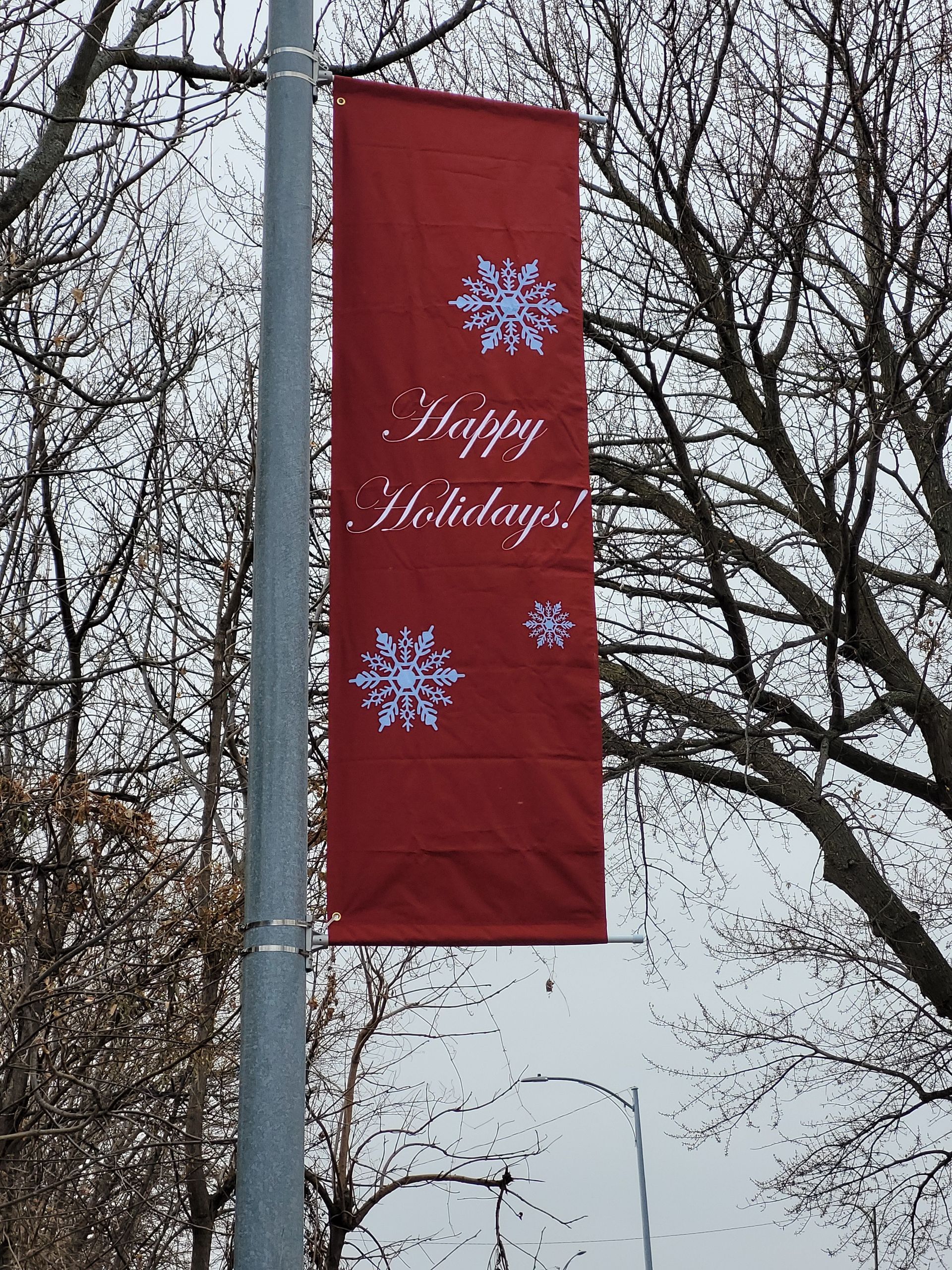 A red banner on a pole that says happy holidays