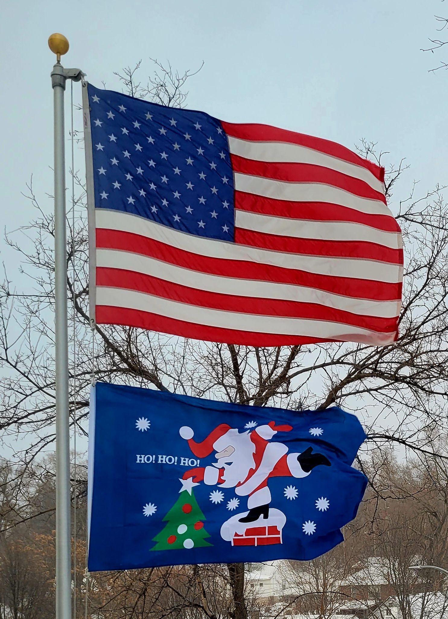 An american flag and a christmas flag are on a pole