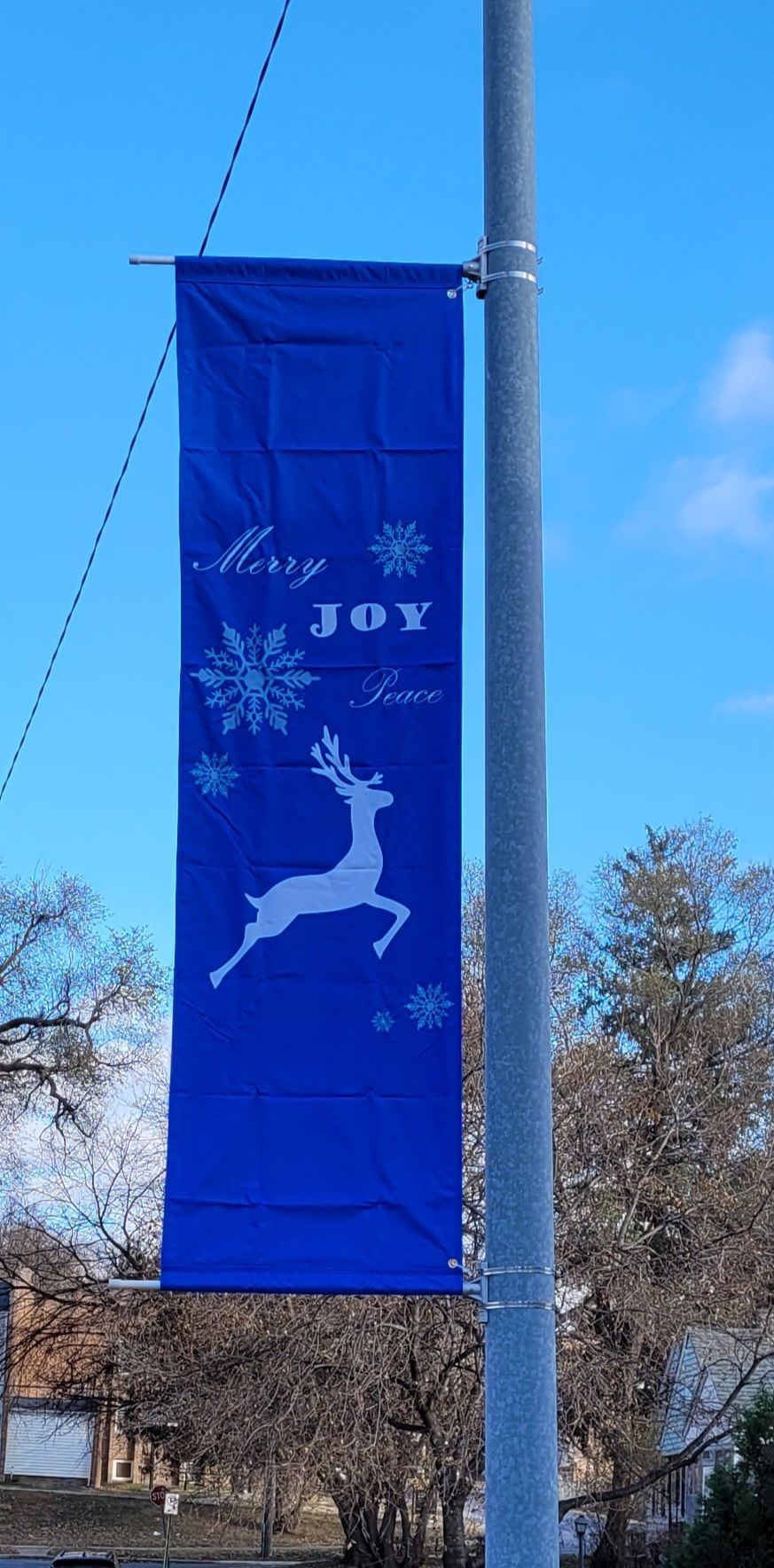 A blue banner with a deer and snowflakes on it is hanging on a pole.